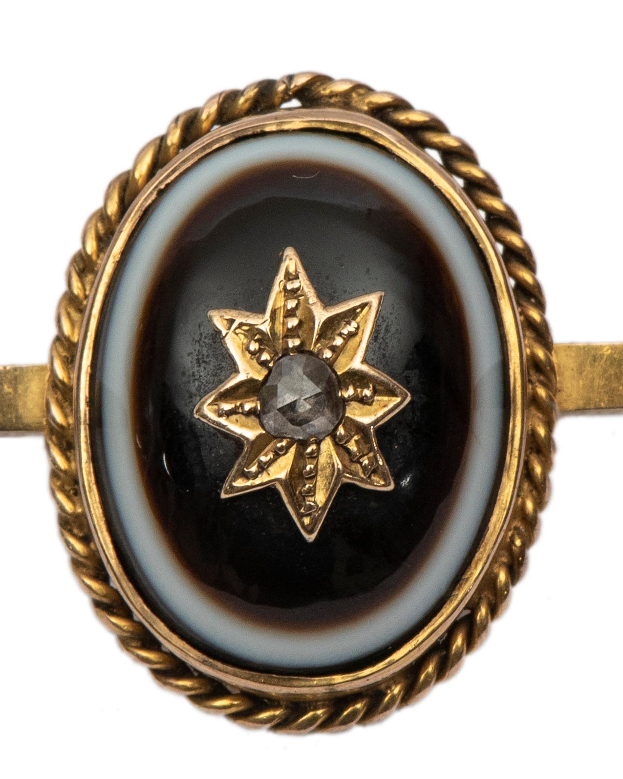 This late Victorian bar pin is set with an oval bull's eye banded agate centered by a rose-cut diamond on a gold star motif, within a twisted ropework border.

-2 1/4 in (5.5 cm) long, oval bezel: 3/4 in. (2 cm) long 

Circa 1890, stamped 9ct