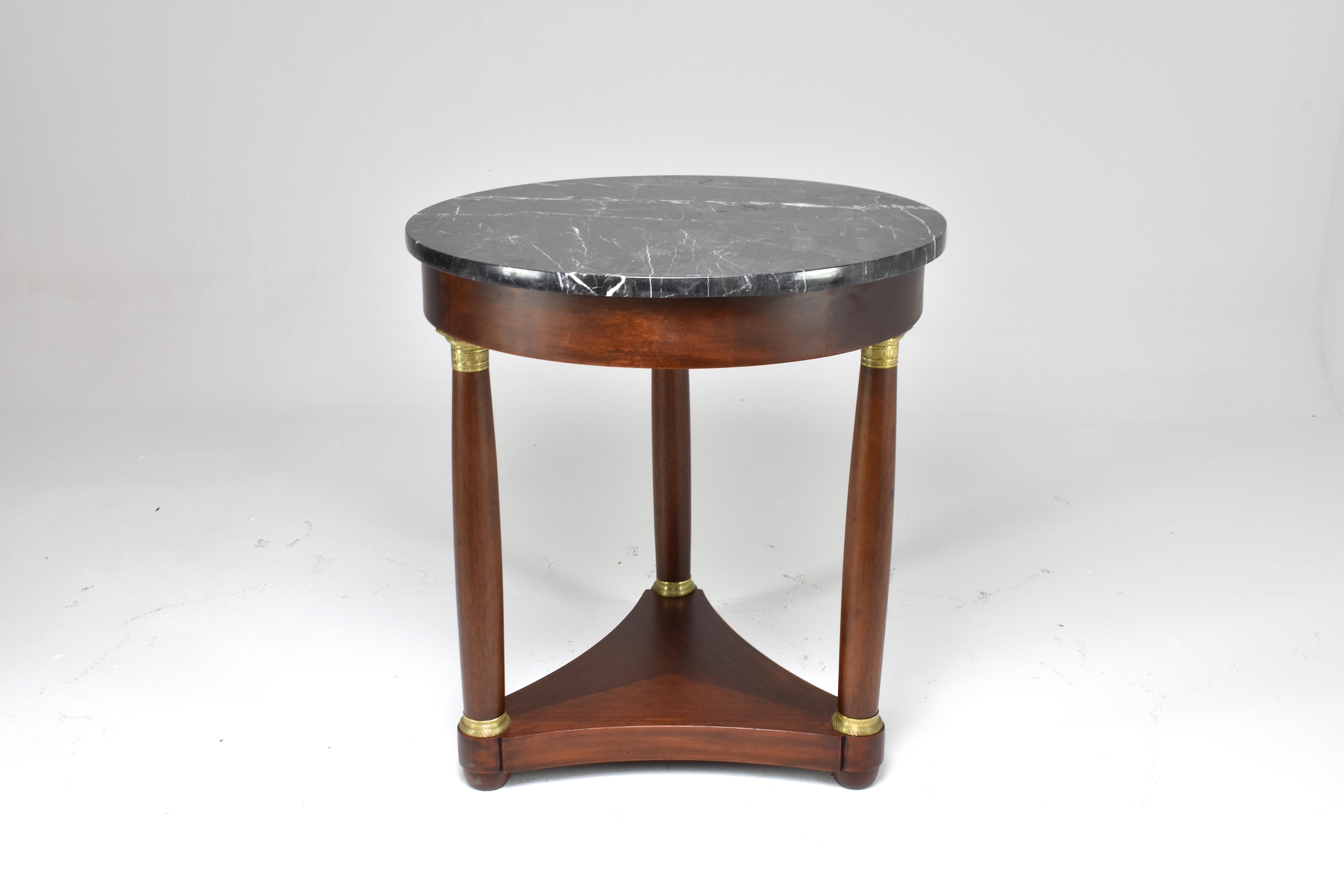 A chic antique pedestal table from the end of the 19th century period designed with tripod legs and hand-sculpted brass details. This beautiful French side table is composed of solid wood and has a black marble tabletop. 
This table can be placed