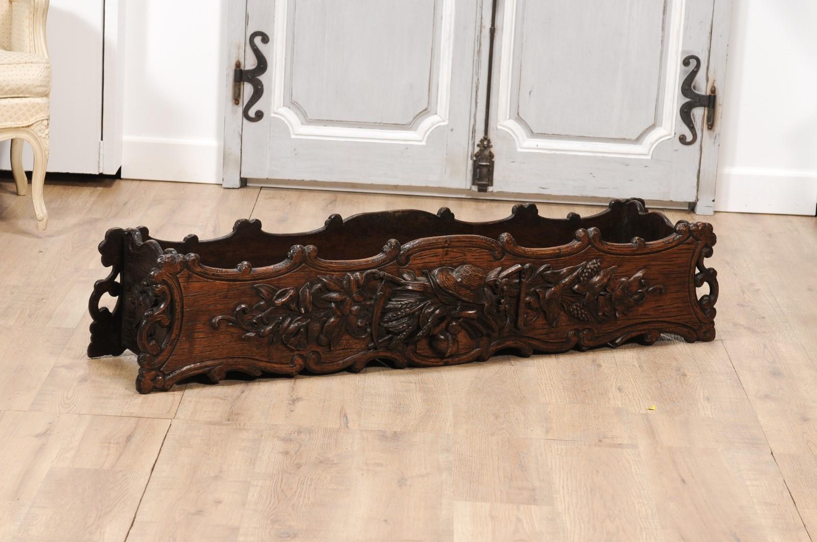 A French oak rectangular planter from circa 1890 with carved gardening-themed frieze in the front. Brimming with charmingly rustic elegance, this French oak rectangular planter from circa 1890 serves as an enchanting homage to gardening. Carved with