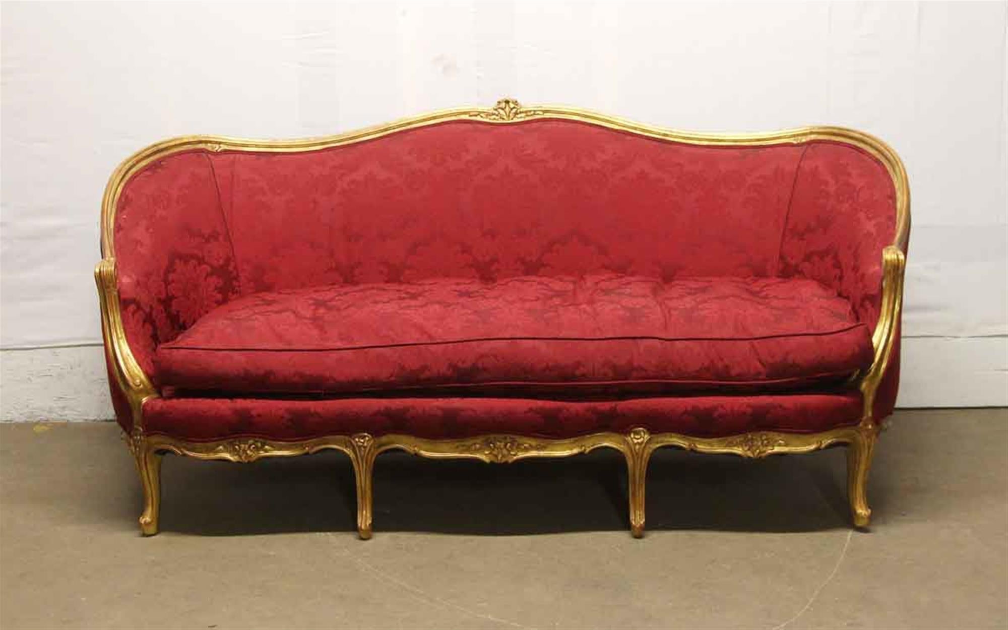1890s sofa or couch with a gilded carved wood frame and red reupholstered floral cushions. This can be seen at our 400 Gilligan St location in Scranton, PA.
