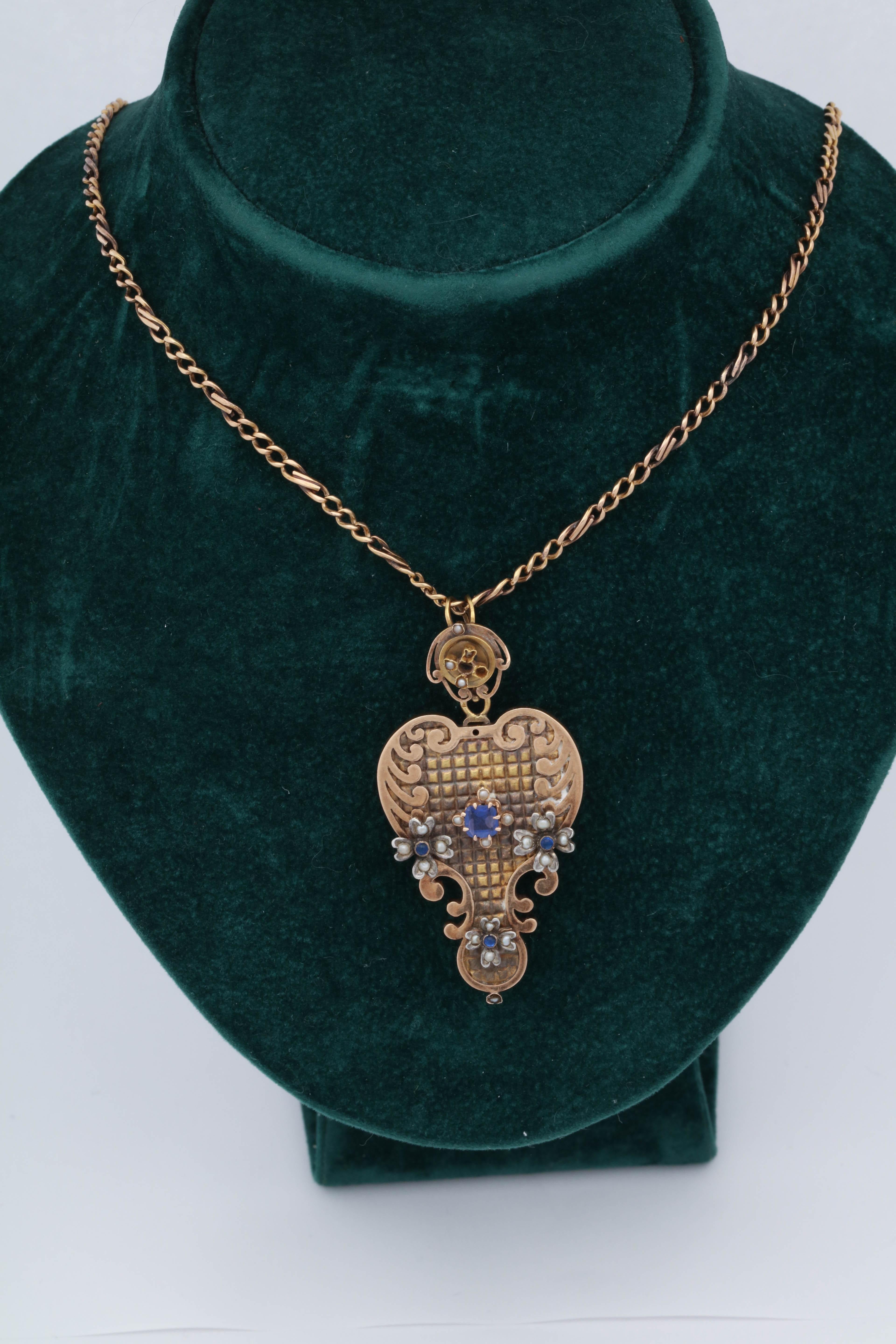 One LadiesAntique Victorian Era 18kt Rose Gold Heart Shaped Handmade And Hand Engraved Locket Embellished With One Square Cut Sapphire Weighing Approximately .50ct. Also Designed With [3] Cabochon Sapphires Weighing Approximately.10 Pts Total