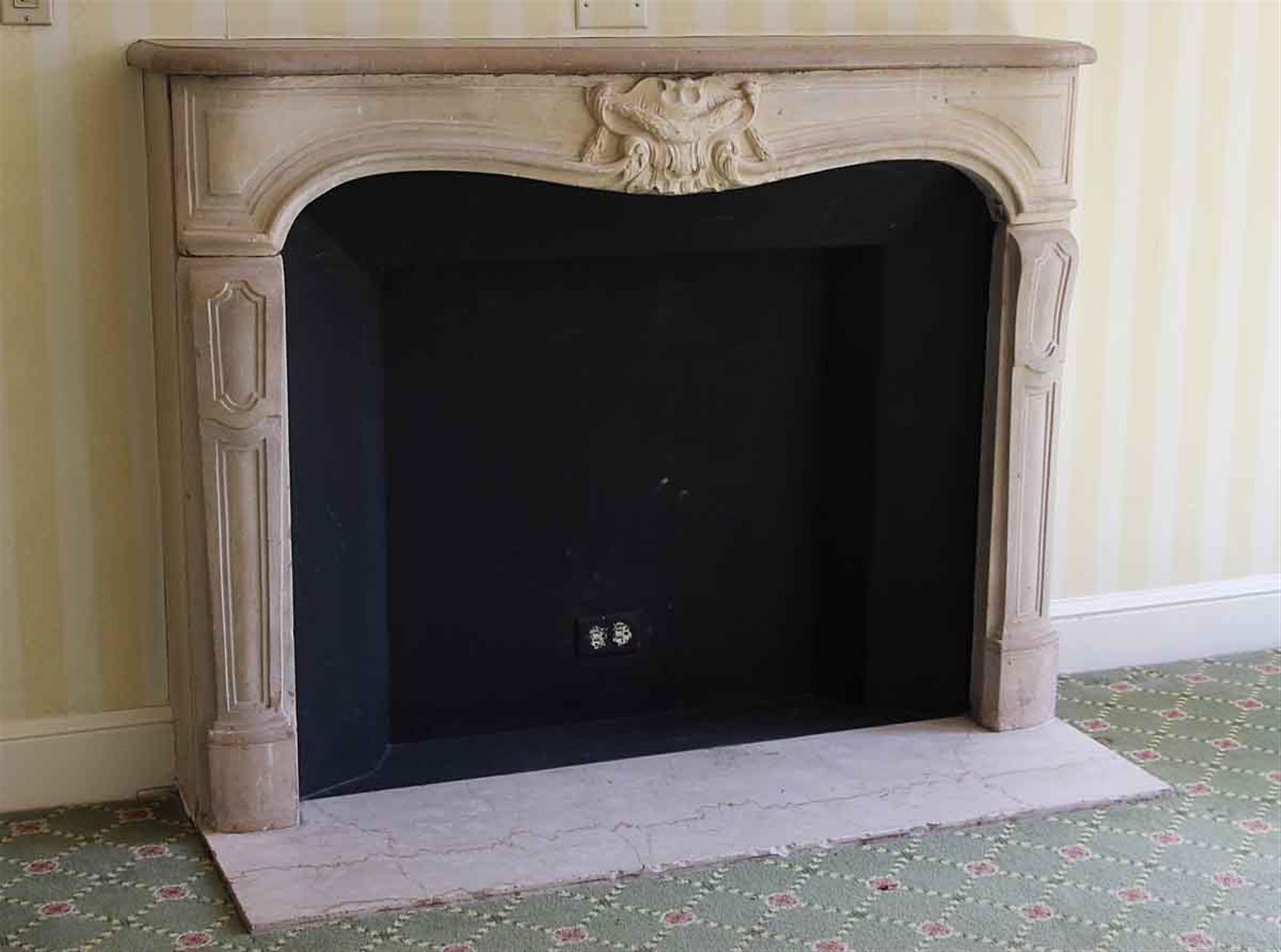 Louis XV carved limestone mantel with its hearth. This mantel was imported from Europe and installed in the Waldorf Astoria Hotel of Park Avenue, New York City in the early 1930s. The stone is in good condition. This mantel is original to suite Y on