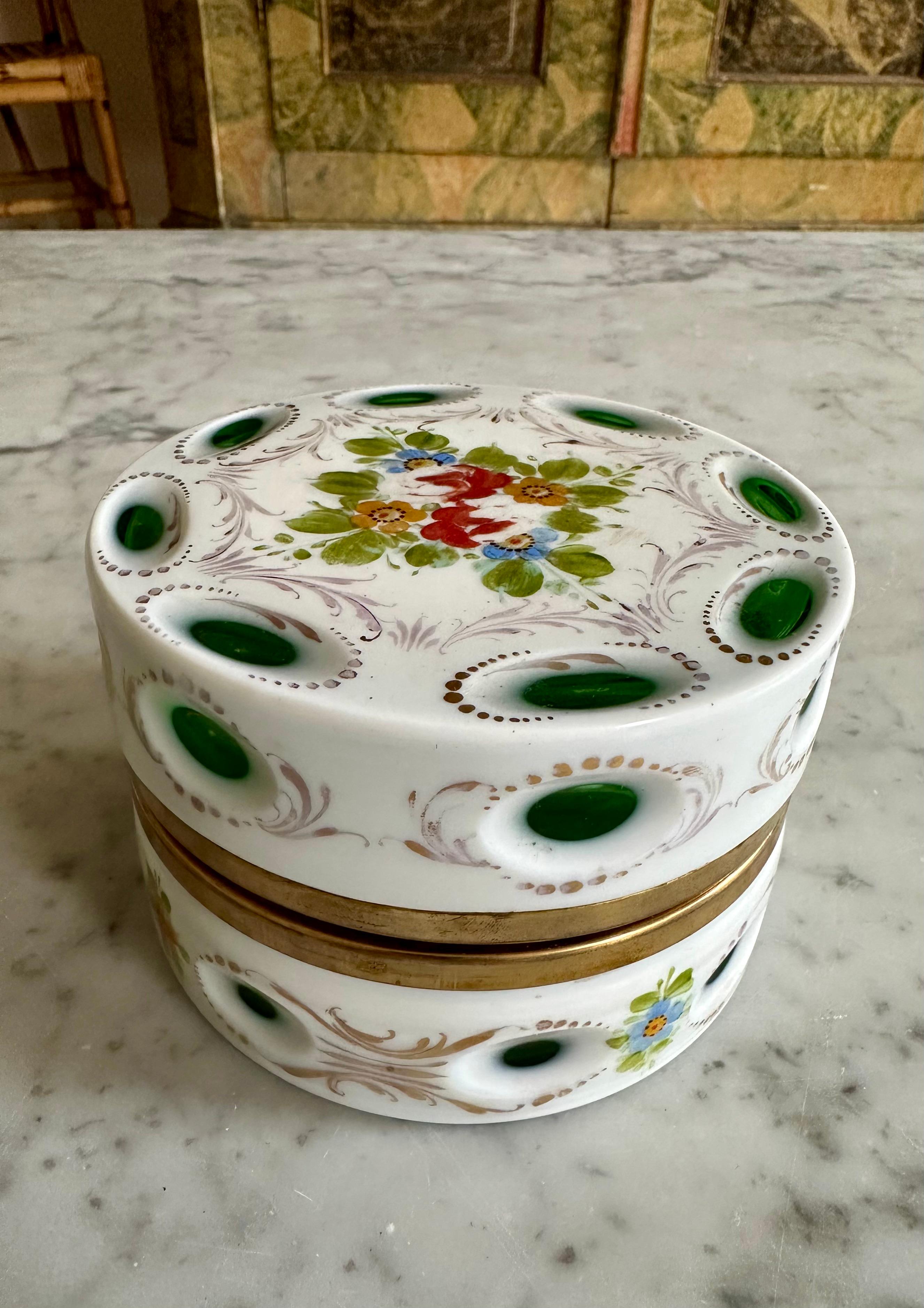 Step into the elegant ambiance of 1890s France with this remarkable opulent round opaline lidded box, adorned with intricate floral paintings and adorned with brass fittings. A testament to meticulous craftsmanship, this box boasts a unique