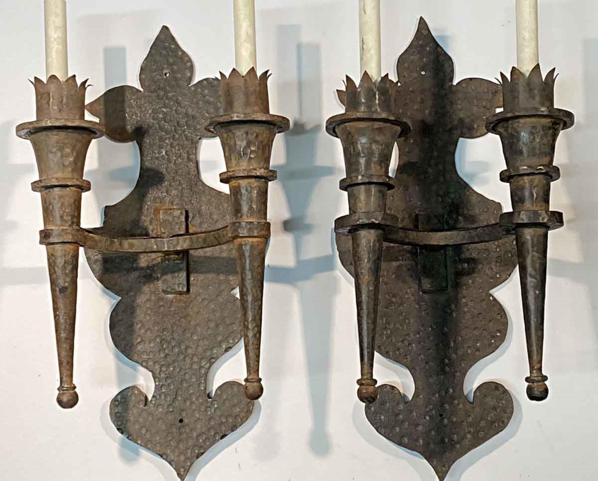 1890s over sized hand hammered wrought iron sconces with torch two light arms. From France. Price includes restoration. This can be viewed at our Scranton, Pennsylvania location. Please inquire for the exact address.