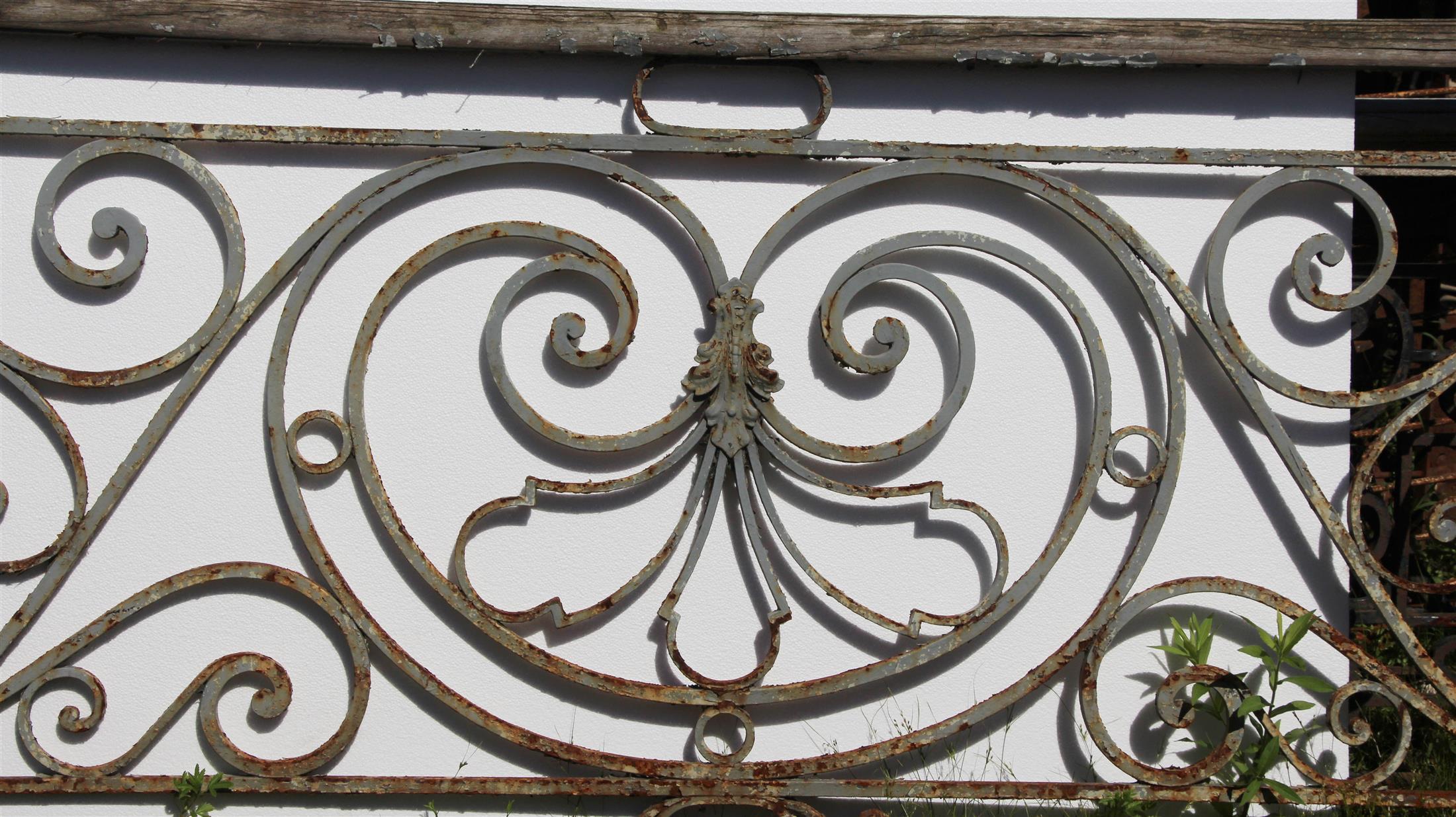 1890s Rococo style gray painted balcony railing with amazing hand-wrought iron detail and a wooden top. There is some rust from age and use. This can be seen at our 400 Gilligan St location in Scranton, PA.