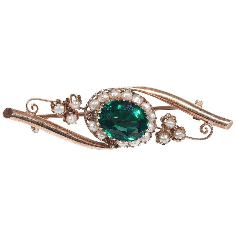 Classic central entwined design, centered by a claw set oval shape mixed cut green tourmaline bordered by a pearls frame, accented by pearl set clovers at the sides to a carved gallery.

Mounted in plain rose gold.

5.4 cm long 

Weight: 4.6 gr