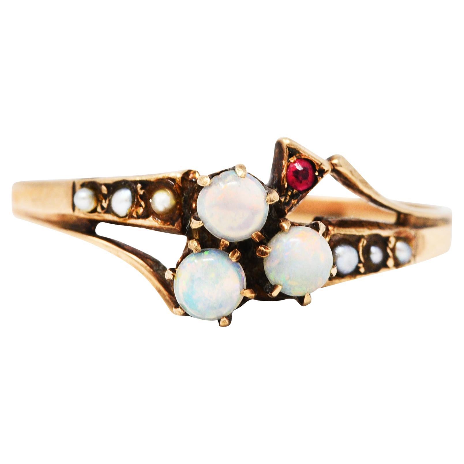 Ring depicts a clover motif comprised of three 3.0 mm round opal cabochons

Well matched in white body color with moderate to strong spectral play-of-color

Clover stem is accented by a bright red round cut ruby

With split bypass style shoulders