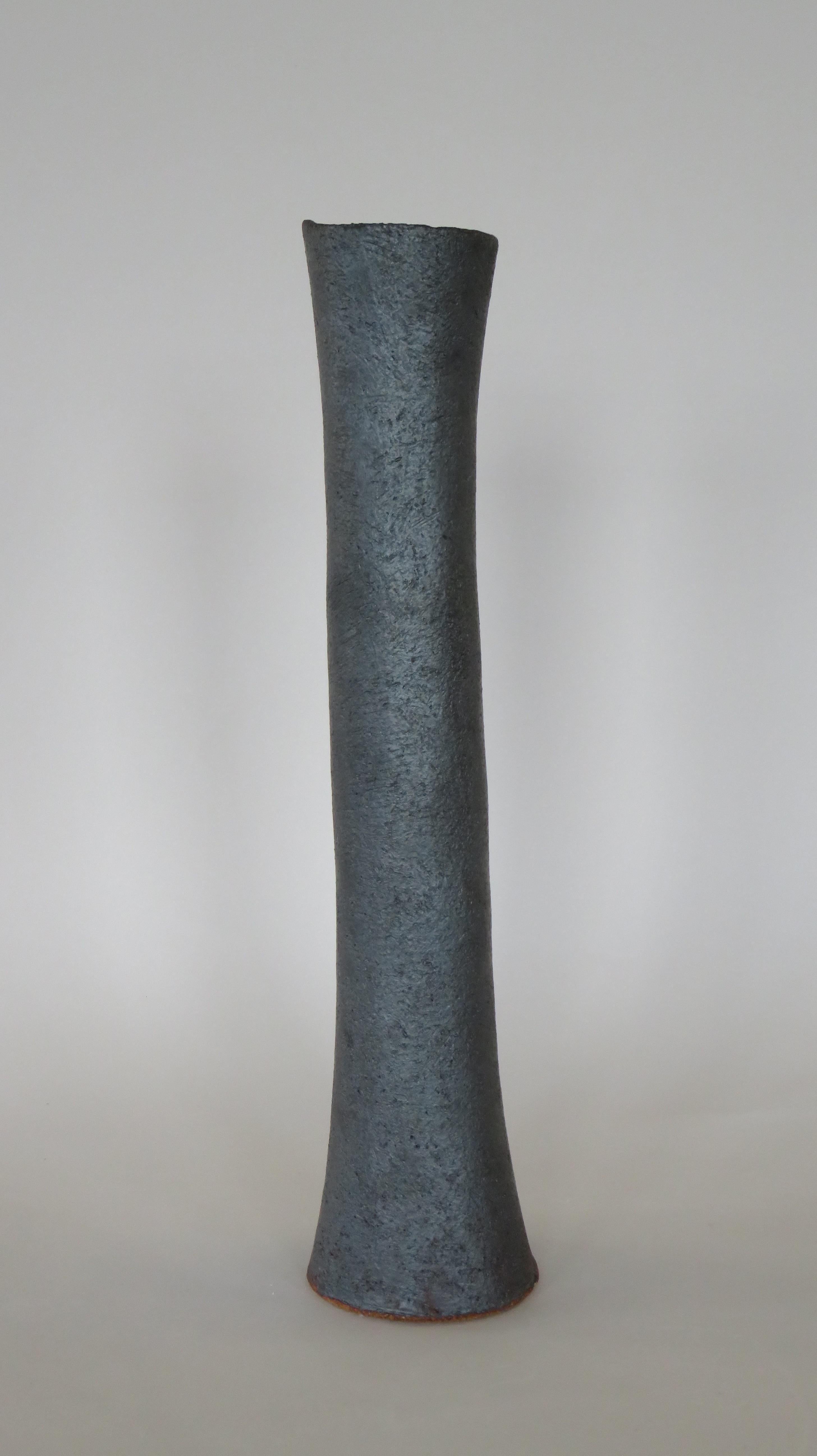 These tall vases in a metallic black glaze over stoneware are weighted on the bottom for tall floral arrangements or branches. Each surface is scraped to show the texture and tone of the clay, with varying bases or knobby edges. The top rims are