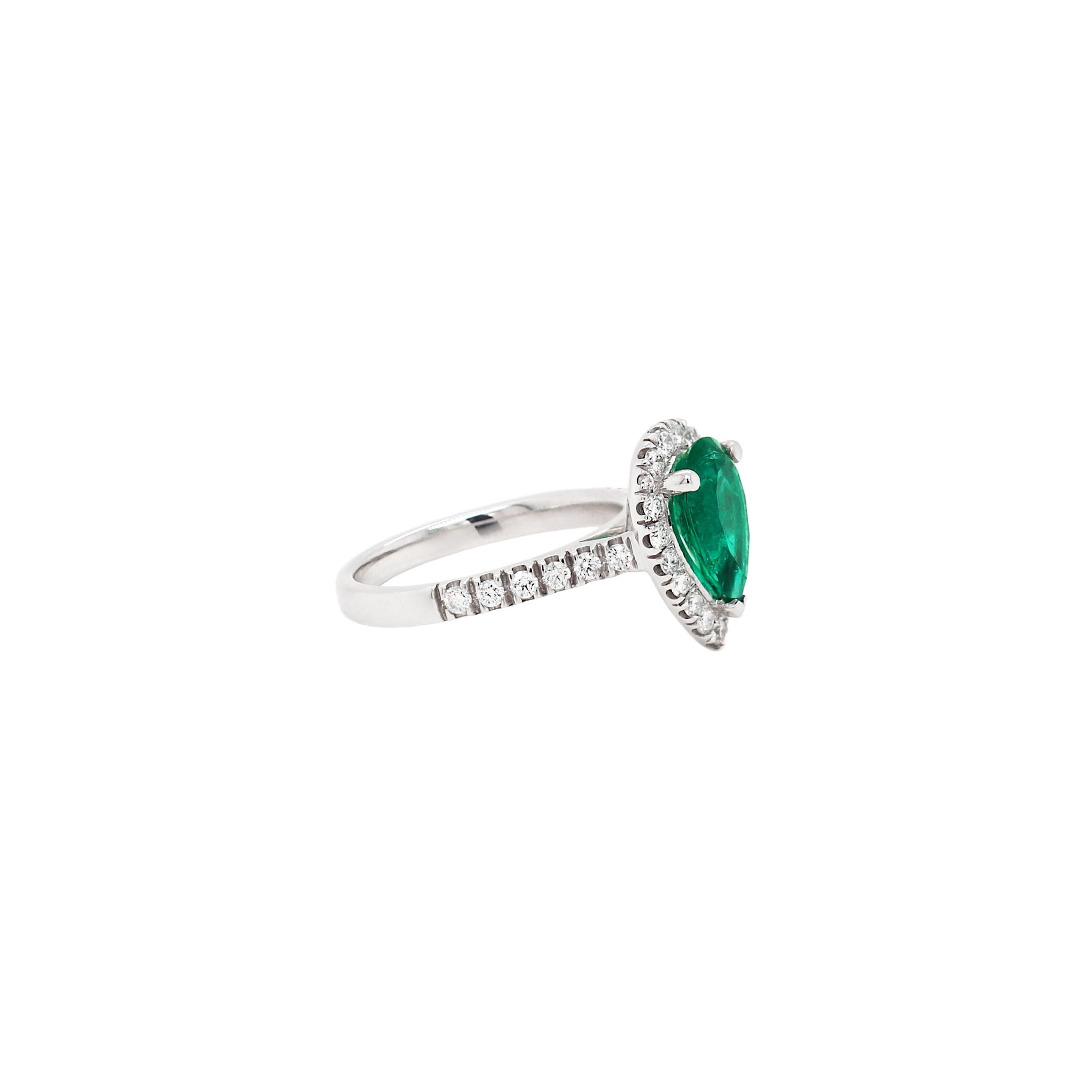 This beautiful engagement ring features a vibrant green pear shaped emerald weighing 1.89ct in a three claw open back setting. The emerald is wonderfully surrounded by 19 round brilliant cut diamonds and further accompanied by 5 round brilliant cut