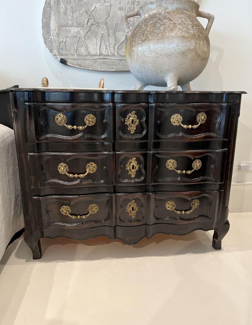 Ornate brass pulls and lock escutcheons on a handsome high gloss black chest.
