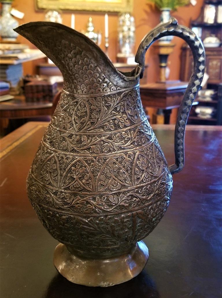 Presenting a gorgeous 18th century Indo-Persian bronze pitcher.

From circa 1780, this pitcher was most likely made in Northern India and is heavily inspired by Persian or Islamic influences.

Bronze with copper and brass it is heavily covered