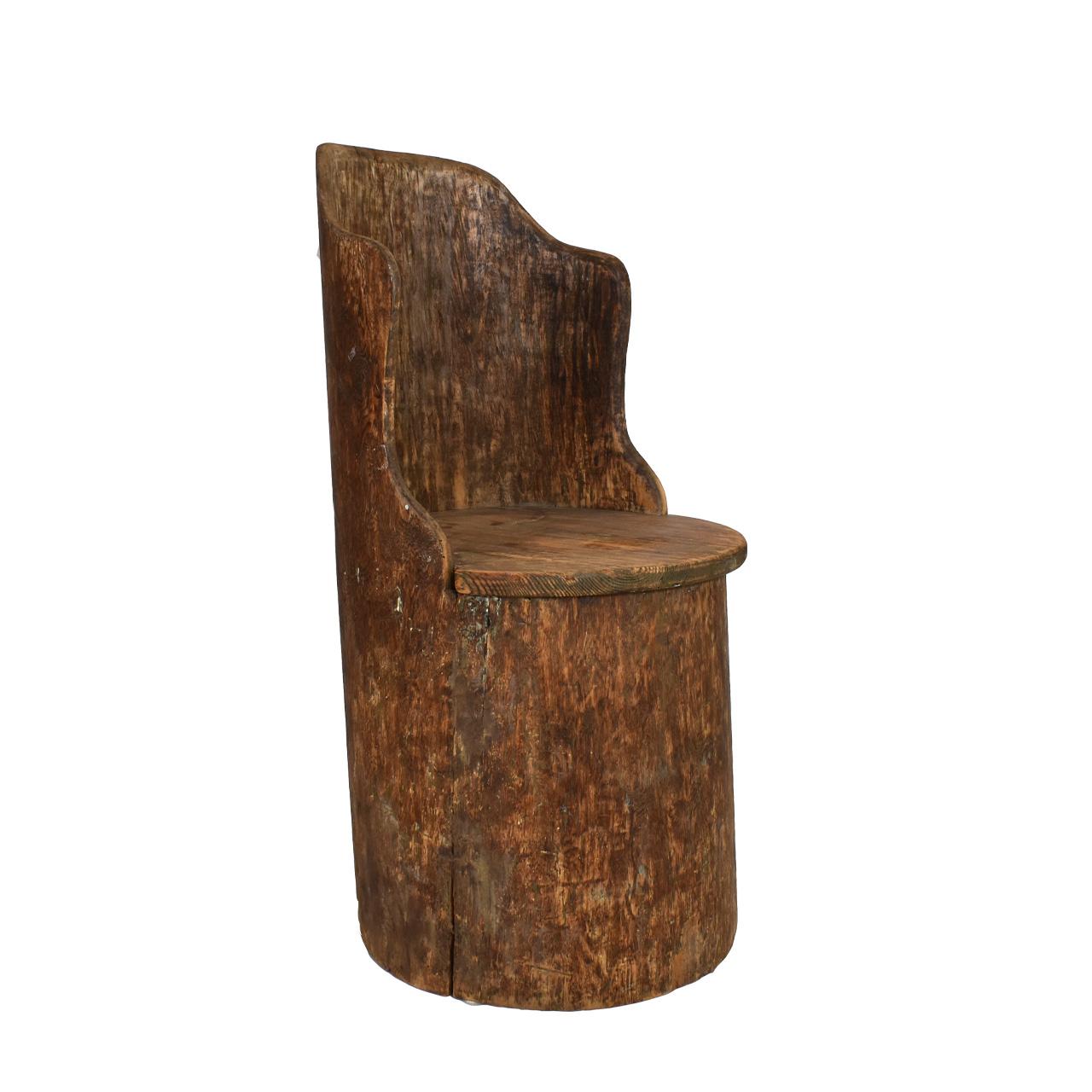 A Swedish Kubbestol chair carved from a tree trunk. The bottom is hollowed and top carved to make the back. Seat is removable so it can be used for storage. Considered Swedish folk art.