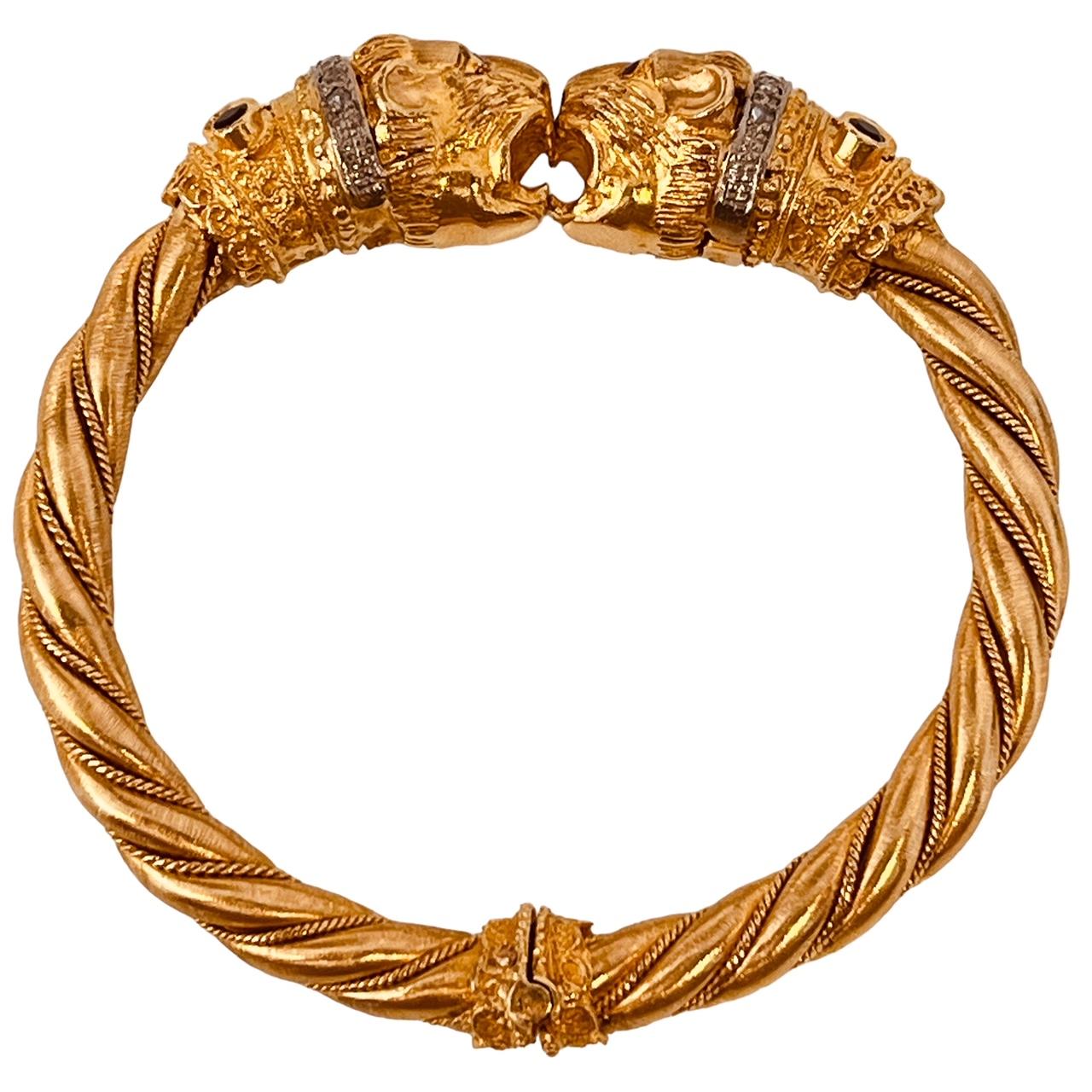 An 18ct yellow gold, twisted bangle with lion-head terminals. The collars set with diamonds, sapphires and emeralds and with ruby eyes. Circa 1969/70. 63.7 grams. Inner diameter approximately 5.5cm. With maker's mark and 