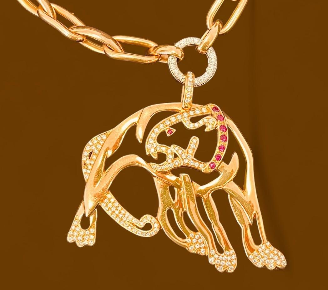 18 carat gold chain of open links to a suspending ring of diamond and to a diamond & ruby set open work pendant of a Jaguar. 43cm long. Total weight of 73.8 grams. Aprox. 1.8 carat diamonds. Aprox. 0.17 carat ruby. Pendant dimensions: 6.5cmx7cm.