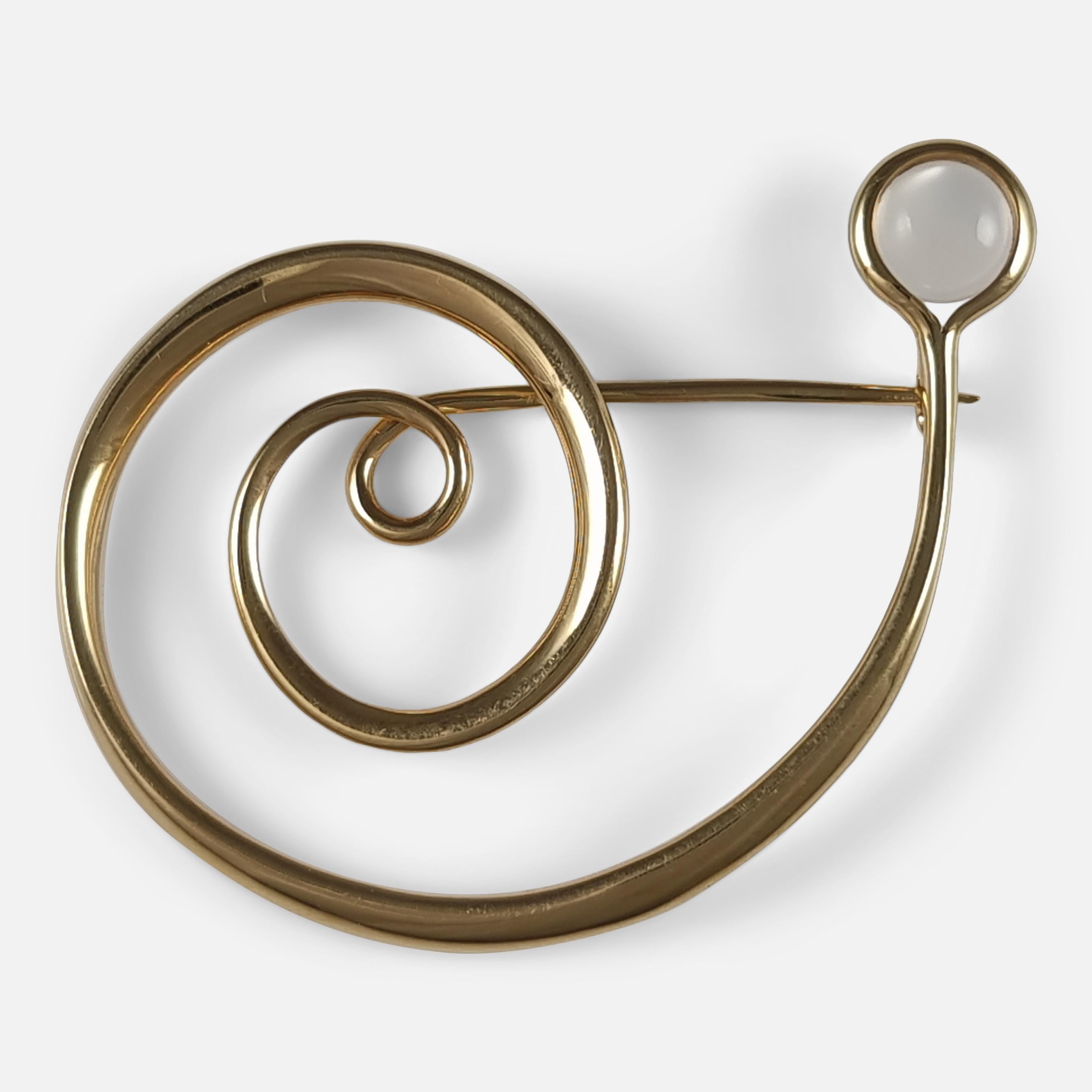 An 18ct yellow gold and moonstone cabochon spiral brooch #1427, designed by Vivianna Torun Bülow-Hübe for Georg Jensen.

The brooch is stamped with the Georg Jensen mark used since 1945, '750', '1427', & 'TORUN'. Also hallmarked to the pin with