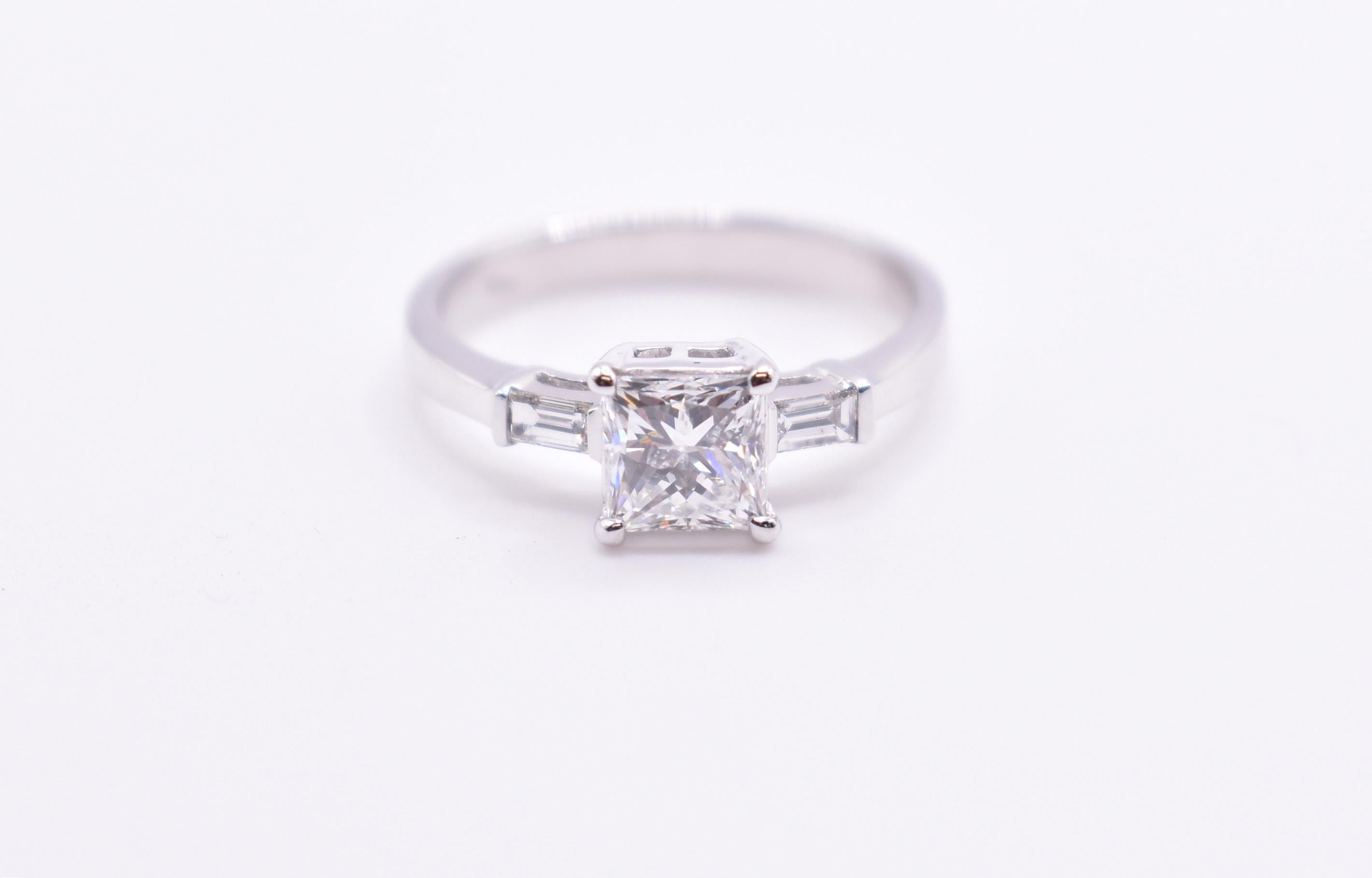 On offer for sale is a splendid 18k white gold 1ct princess cut diamond engagement ring, having a princess cut diamond to the centre, with baguette cut diamonds on either side.

1 x 1.01ct princess cut diamond
2 x 014ct baguette cut diamonds
SI 2