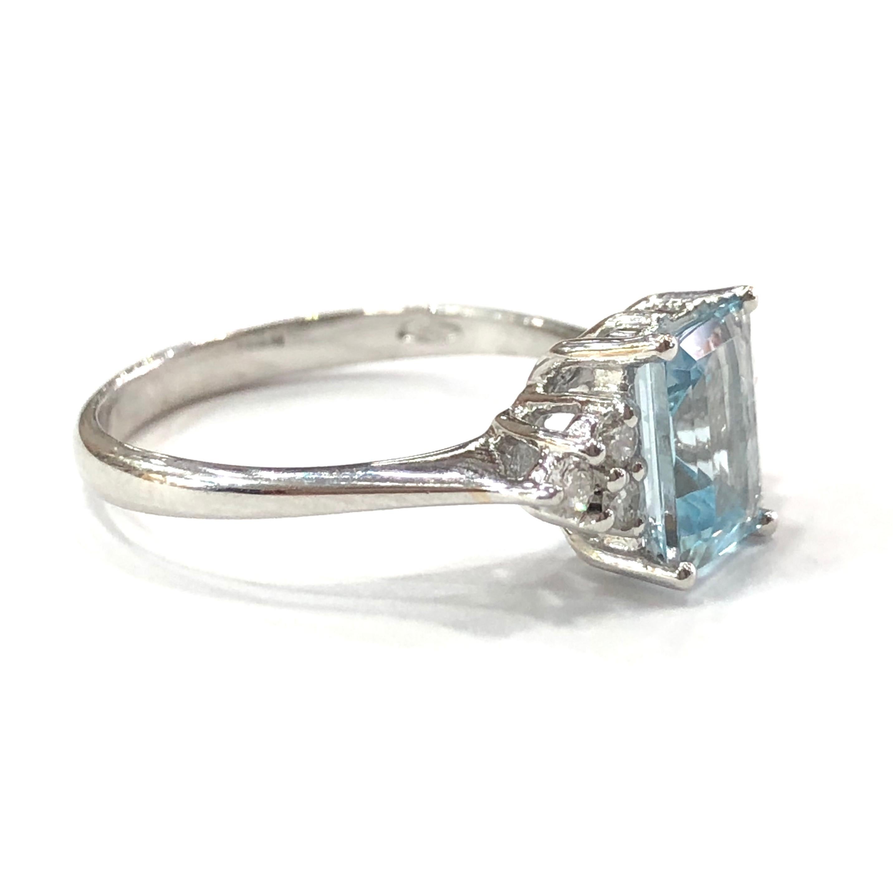 18ct White Gold Aquamarine and Diamond Ring. Set with a central 8 x 6mm emerald cut Aquamarine set in a four claw setting. With six round brilliant cut Diamonds set on the shoulders in a peg setting. (three on each side)
With a full english