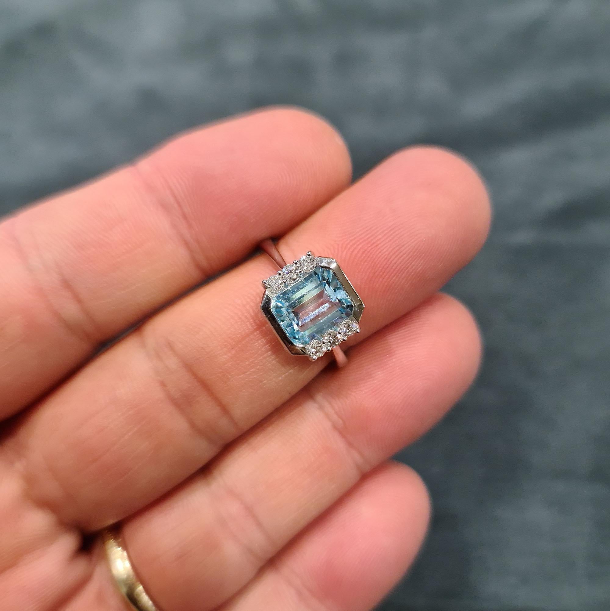 A fine and impressive modern dress / cocktail ring in 18-carat white gold. The bright and lively central emerald-cut aquamarine, mounted in a bezel setting, flanked at each side by three round-brilliant-cut diamonds. Polished 18-carat white gold