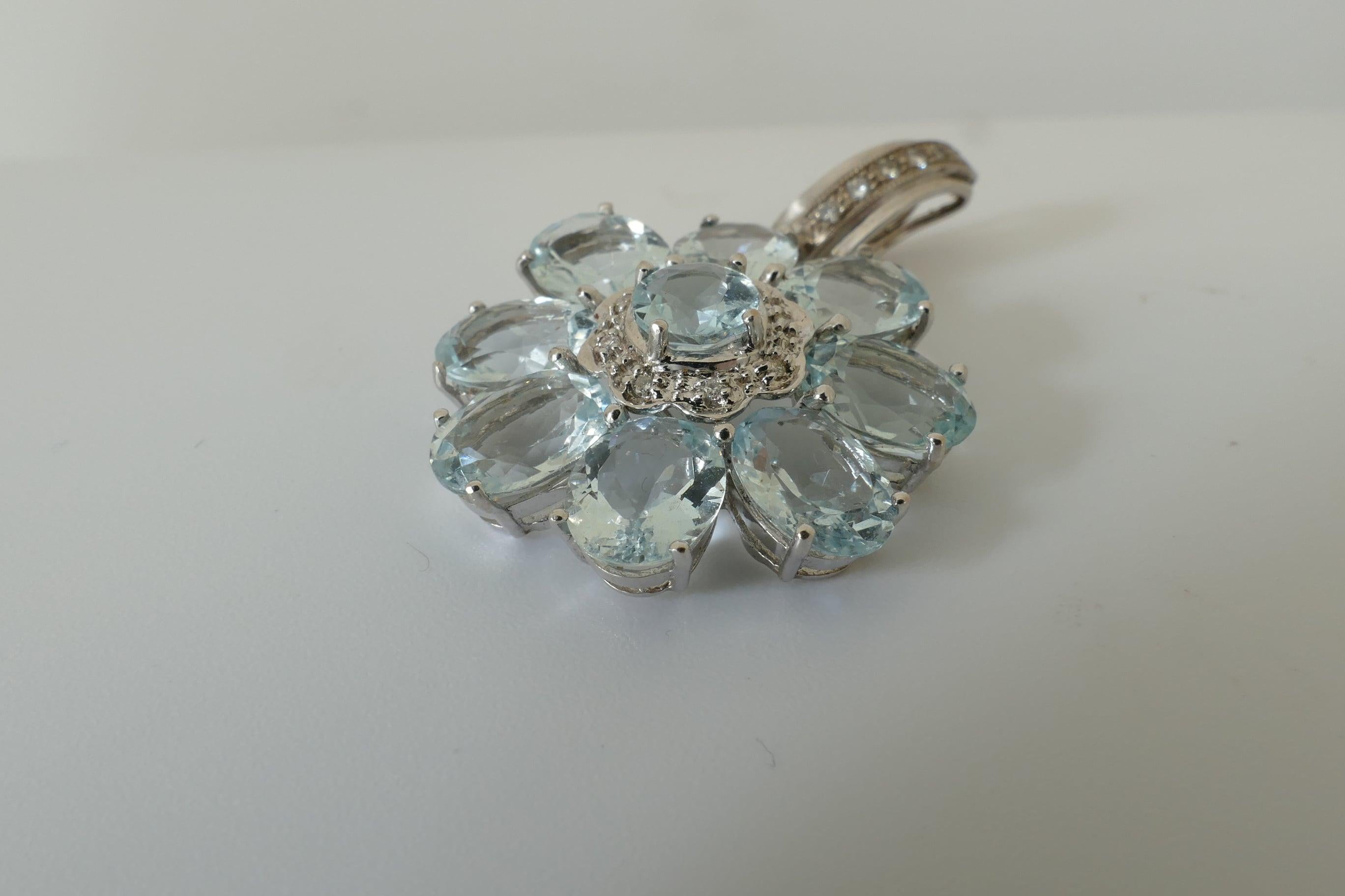 Comprised of multiple - 20.16 carats in all - high level Aquamarines set into a beautiful Flower Design this exquisite Pendant is an Enhancer as well. It has a white gold Bale set with 14 round brilliant cut Diamonds, colour G/H; clarity SI1-SI2,