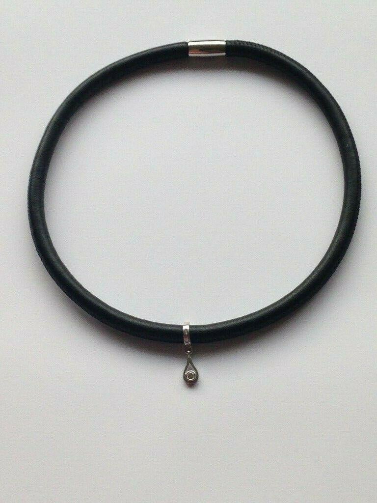 Il ciondolo rimovibile in oro bianco 18ct è di un designer sconosciuto 
Completamente britannico con marchio di garanzia per l'oro 18ct 
Il diamante autentico solitario è di 3 mm - 0,15 carati 
Peso del fascino - 2,34 grammi
Il girocollo è in pelle