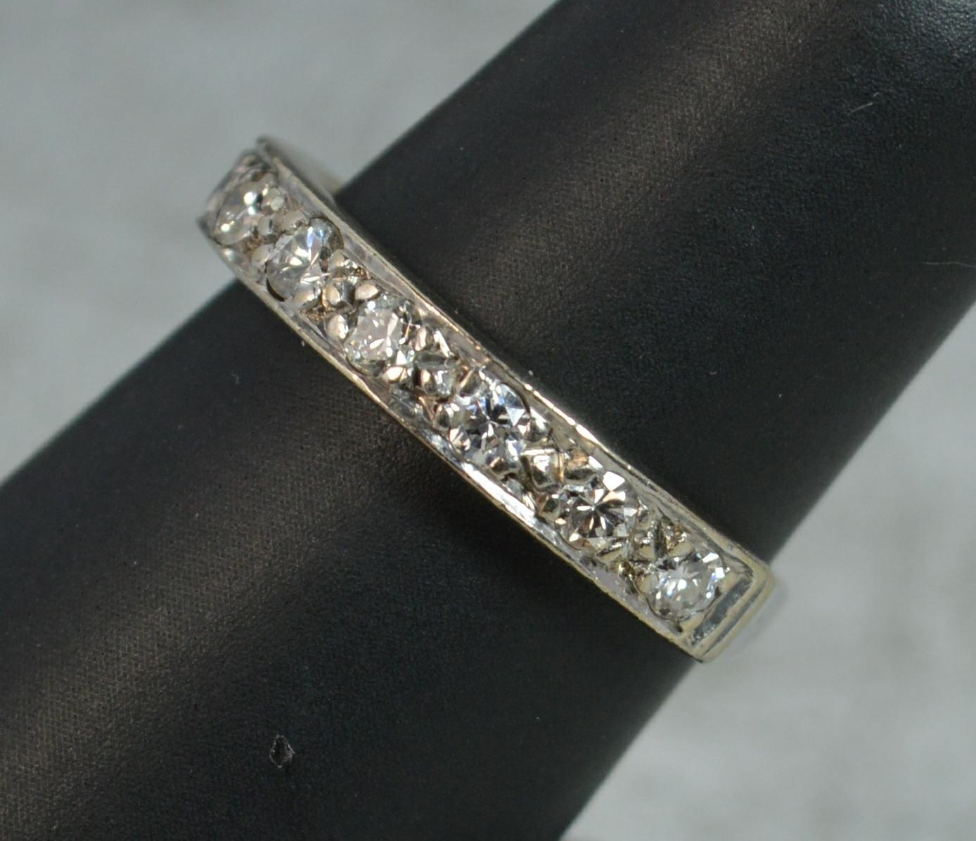 An 18 carat gold and diamond ring.
18 carat white gold example.
Designed with nine natural round brilliant cut diamonds to total approx 0.32 carat.
21mm spread of stones, 3.4mm wide band to the front.

CONDITION ; Very good. Well set diamonds, issue