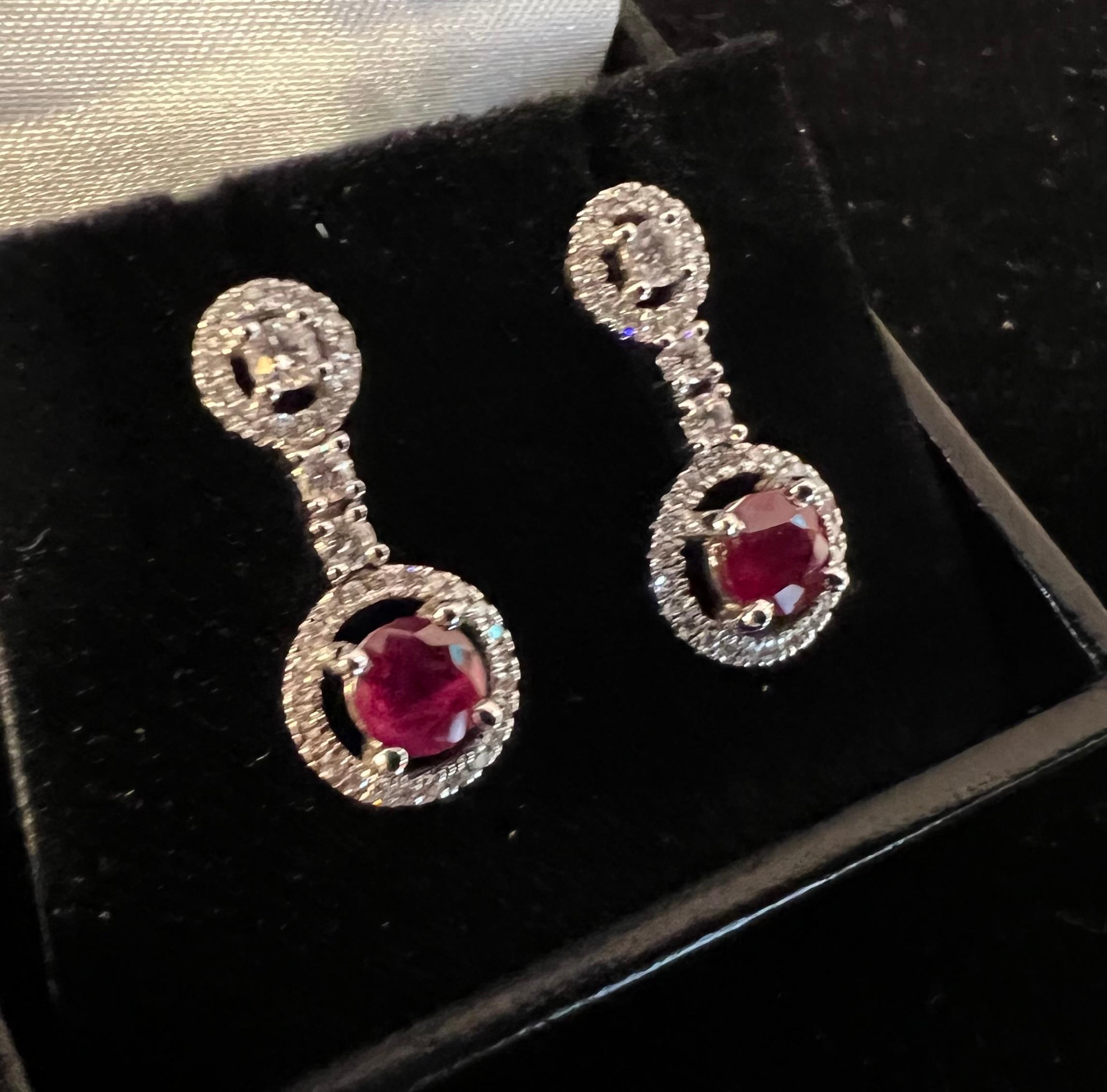 18ct white gold earrings set with two rubies totaling 1.07ct and paved with brilliants totaling approximately 0.47ct. length: 2cm push rod clasp. the ruby surrounded by brilliants: 1cm in diameter