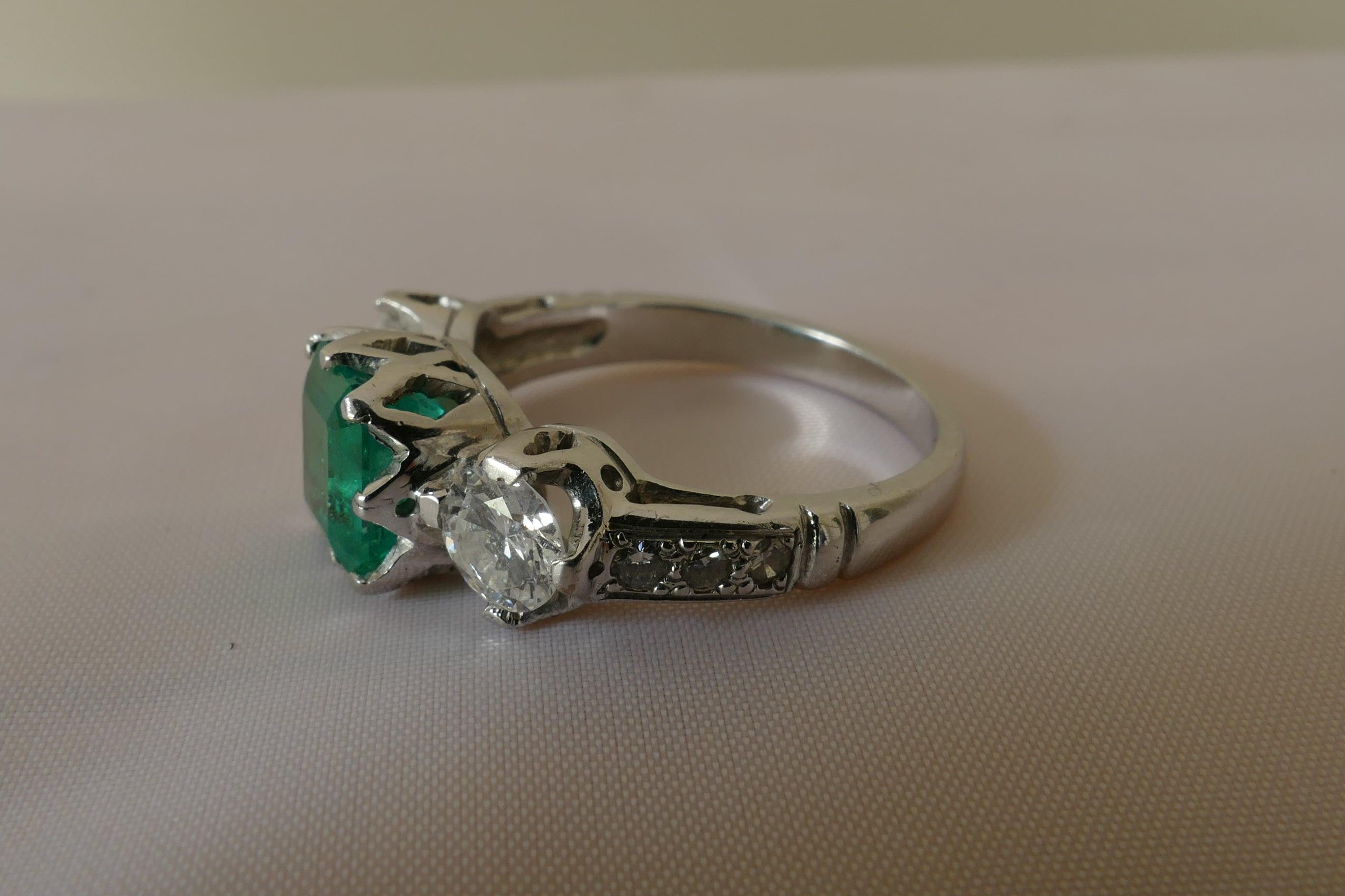This Ring features a high quality Emerald Cut Emerald, 8 claw set of 2 carats.
Fine vivid green colour with 2 Round Brilliant Cut Diamonds of approximately 0.8 Carat in weight H Colour as the surround.
AS well there are 6 Round Cut Diamonds SI