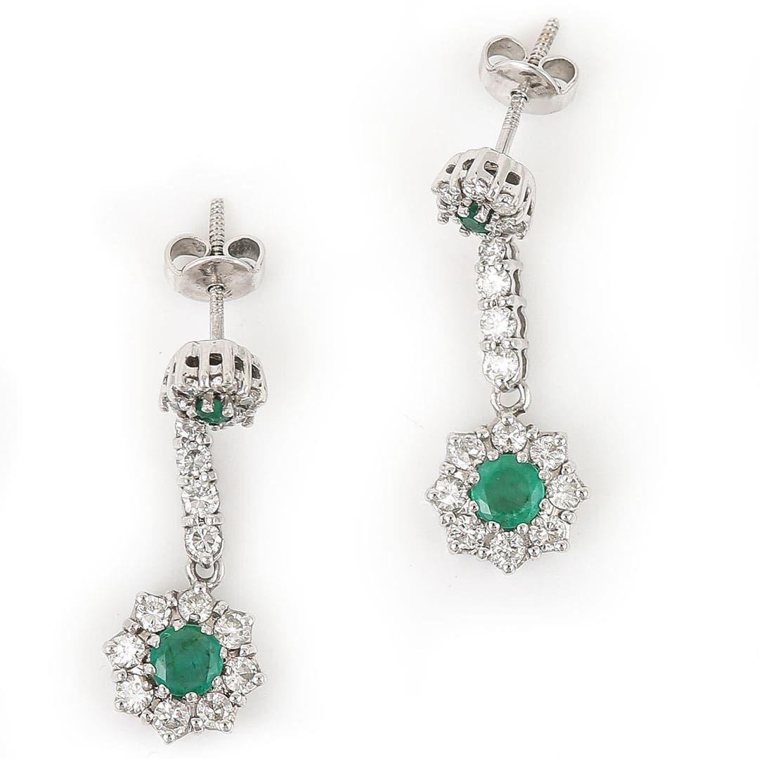An elegant pair of contemporary 18ct white gold emerald and diamond pendant drop earrings. The emerald and diamond cluster heads are adjoined by a diamond set bar to a further round cut emerald and diamond cluster drop. With approx 1ct total of