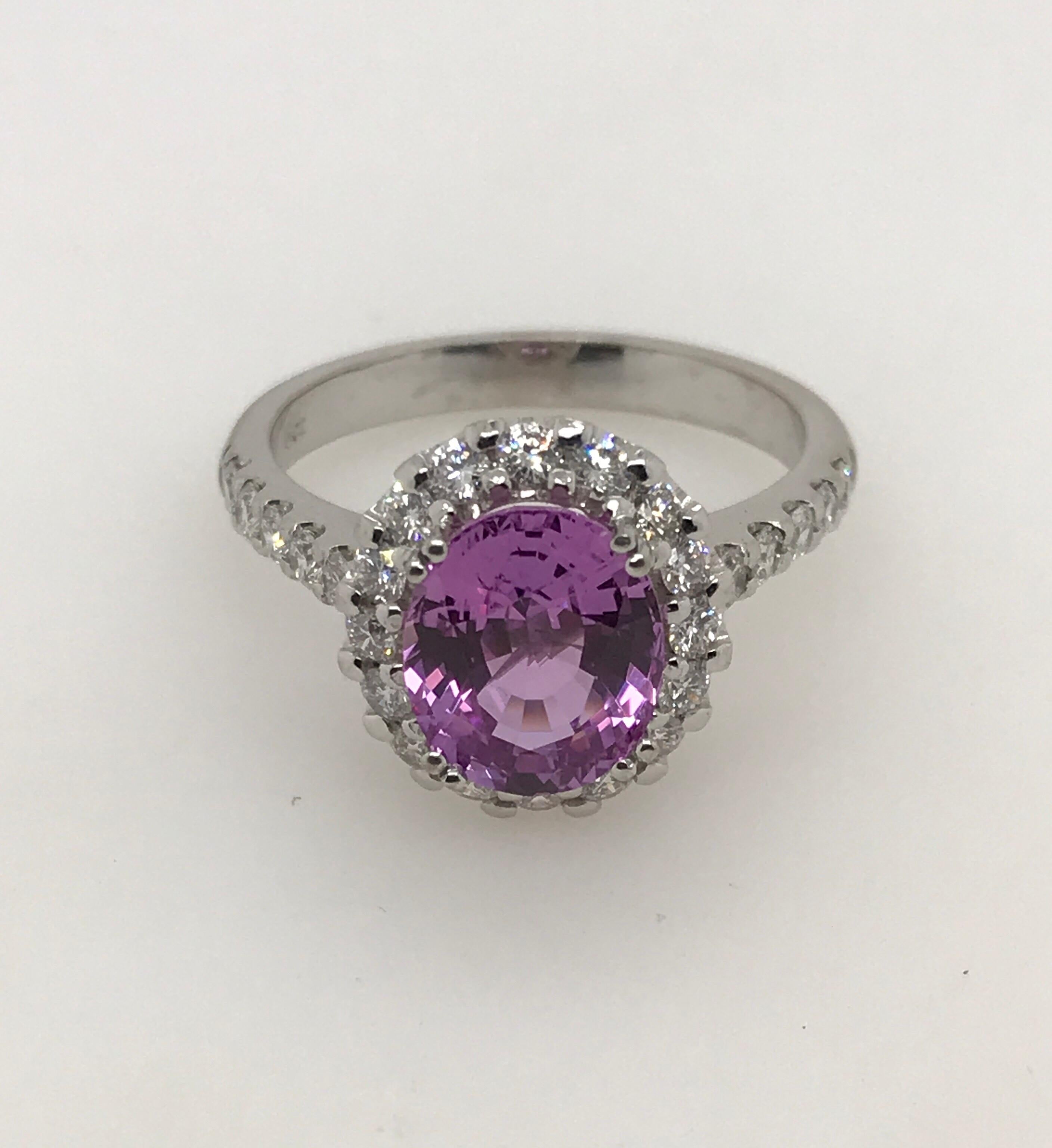 18ct white gold oval pink sapphire and brilliant cut diamond claw set cluster ring. The centre sapphire is 2.89ct and is moderately strong pink in colour.  26 round brilliant diamonds totalling 0.52ct F SI1 surround the centre stone and run down the