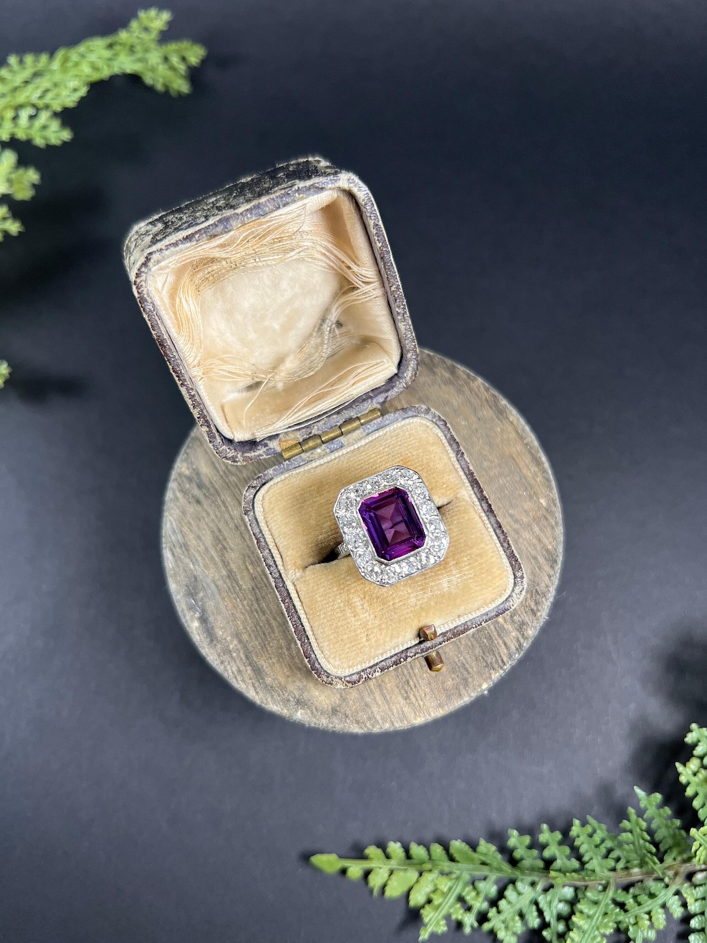 Antique Amethyst Ring 

18ct White Gold & Platinum Tested

Circa 1920s

This stunning antique ring from the 1920s features a beautiful emerald-cut amethyst stone as its centrepiece, surrounded by a rectangular halo of natural old European cut
