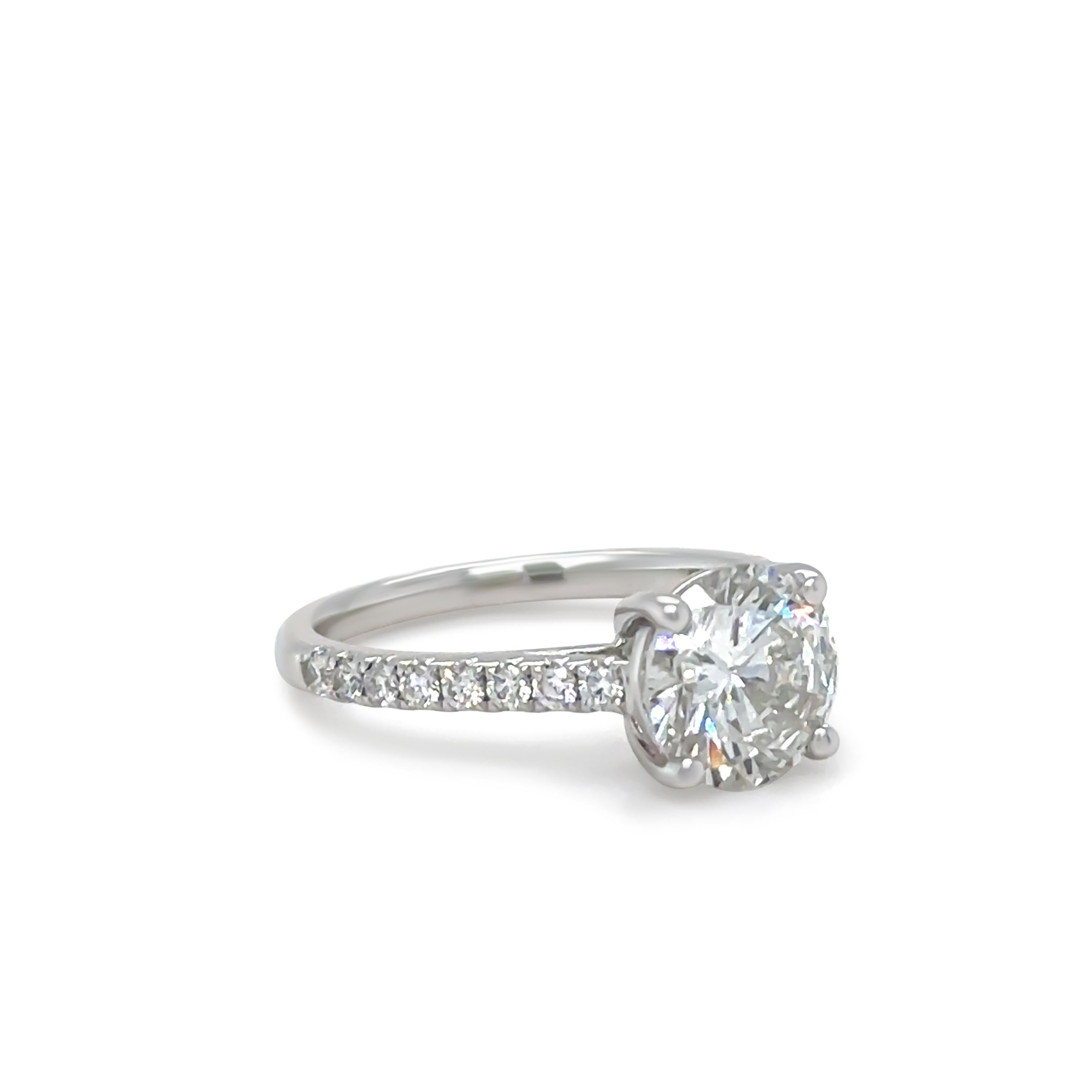 This exquisite handcrafted 18ct white gold diamond ring features a stunning 1.01ct round brilliant-cut diamond, graded F colour and SI2 clarity, securely set in a six-claw coronet setting. The centre stone is elegantly complemented by diamond