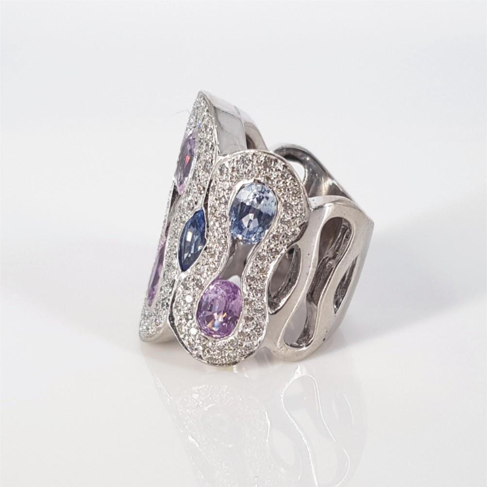 This Chunky bohemian Ring with a touch of pizzazz is made in 18 carat White Gold. The Center stones are 8 Sapphires, 2 Oval Cuts weighing 1.5ct in total, 4 Oval Cuts weighing 1ct in total, and another 2 Marquise Cuts weighing 0.8 Carat. This ring is
