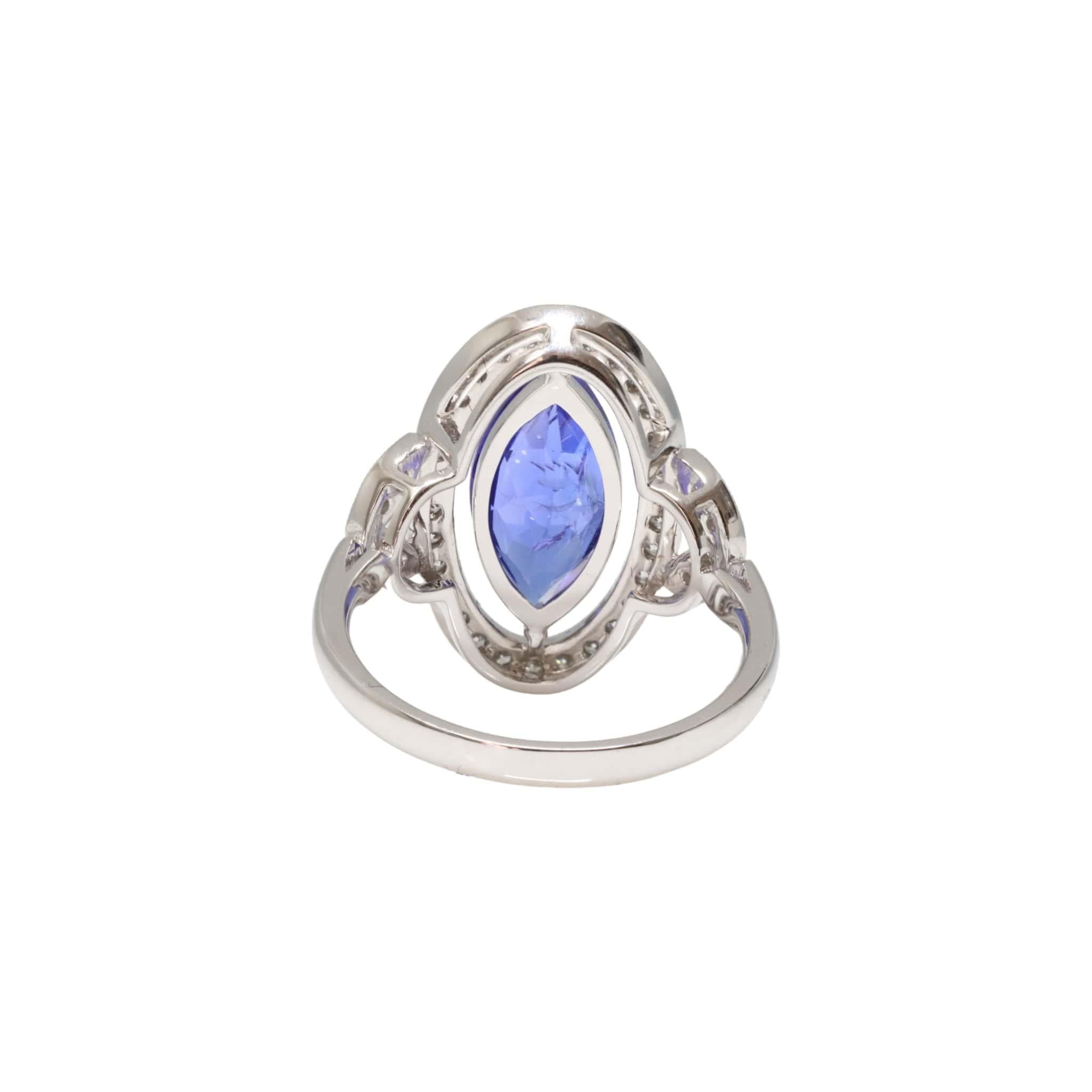 Item 1

One ladies - 18ct white gold dress ring, narrow, half round shank with open back, leaf-shaped shoulders 2 claw with single halo surround, polished finish. The item contains:

One claw set marquise tanzanite, colour is 