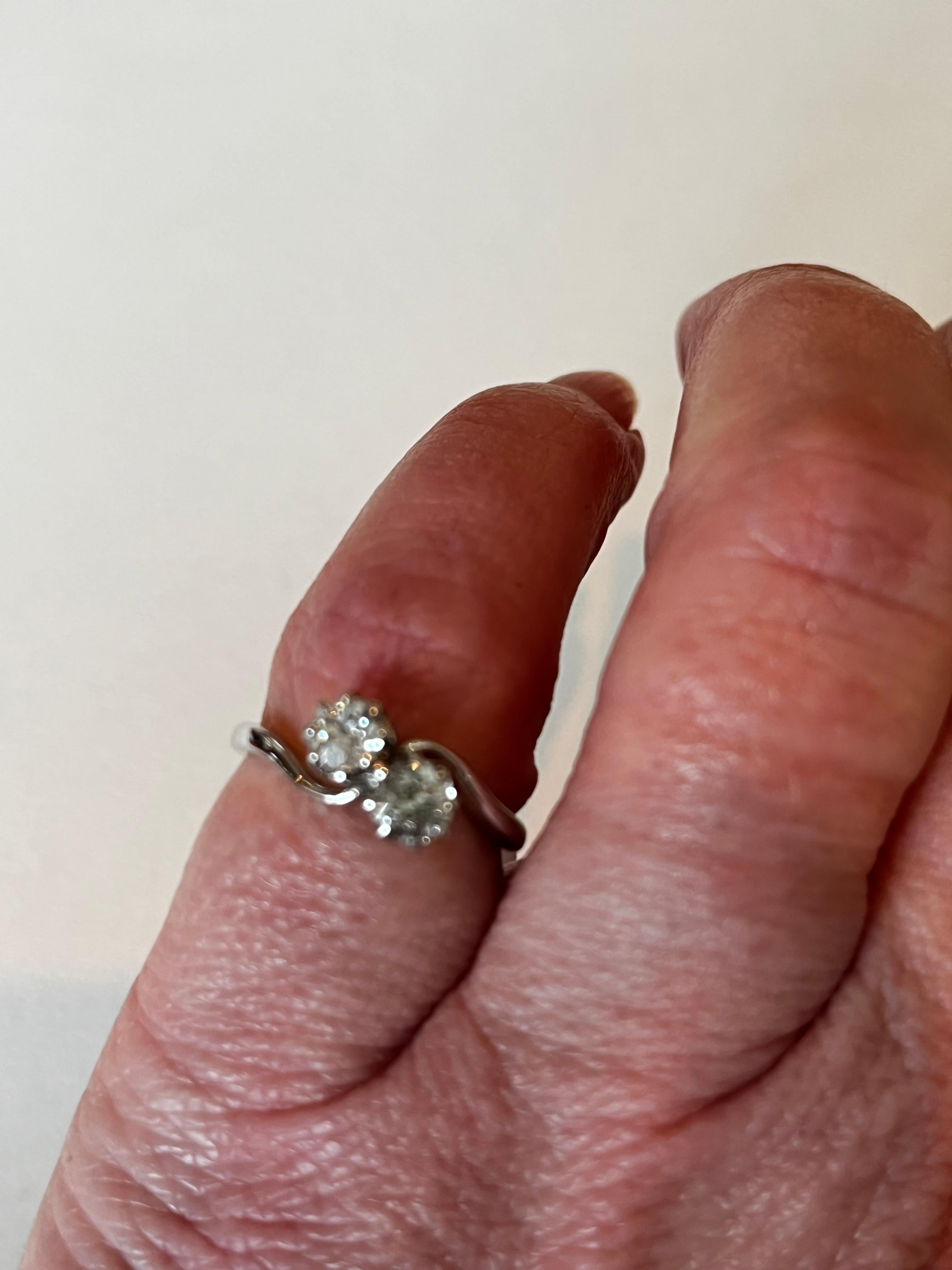 Diese hübsche antike zwei Stein Diamantring ist est .60ct, Klarheit S/I1.  Dieser Ring aus 18 Karat Weißgold wird in der Größe 4,75 (USA) bzw. J (Großbritannien) geliefert.  Datiert ca. 1950er Jahre.
