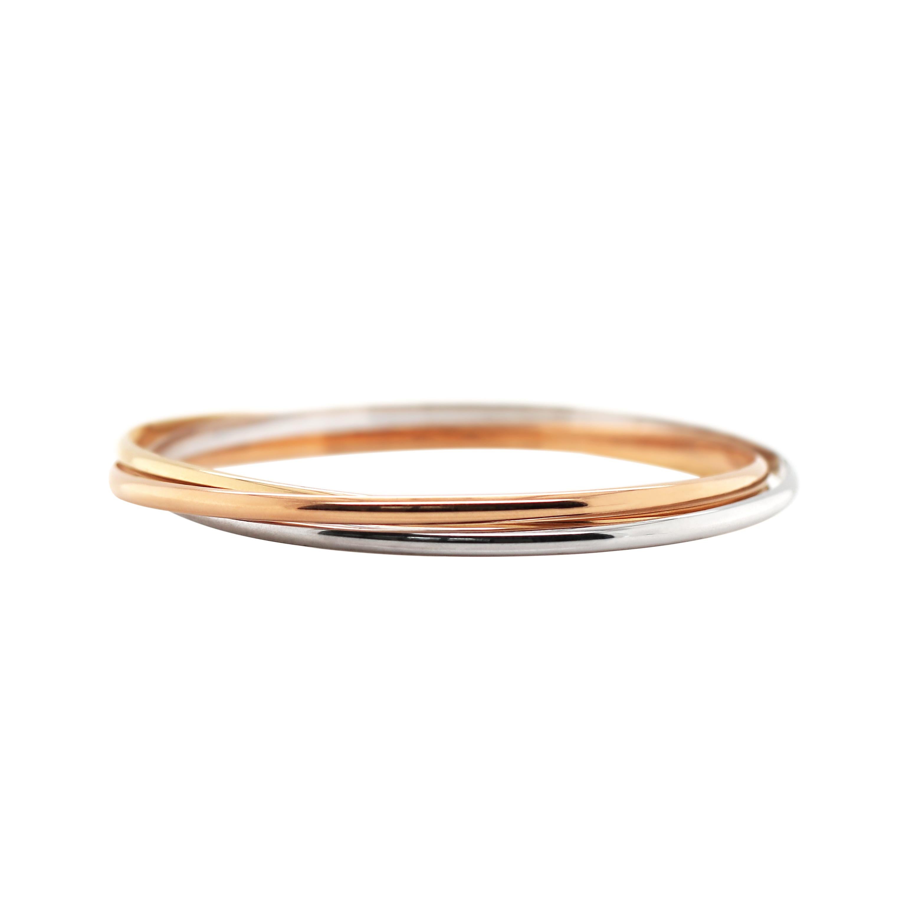 This trinity bangle is composed of three plain 18 carat gold bangles, one white, one yellow and one rose connected to make a classic Russian bangle. Each bangle measures 3mm in width and 7cm in diameter and weighs a total of 35.87g. Stamped 18K.