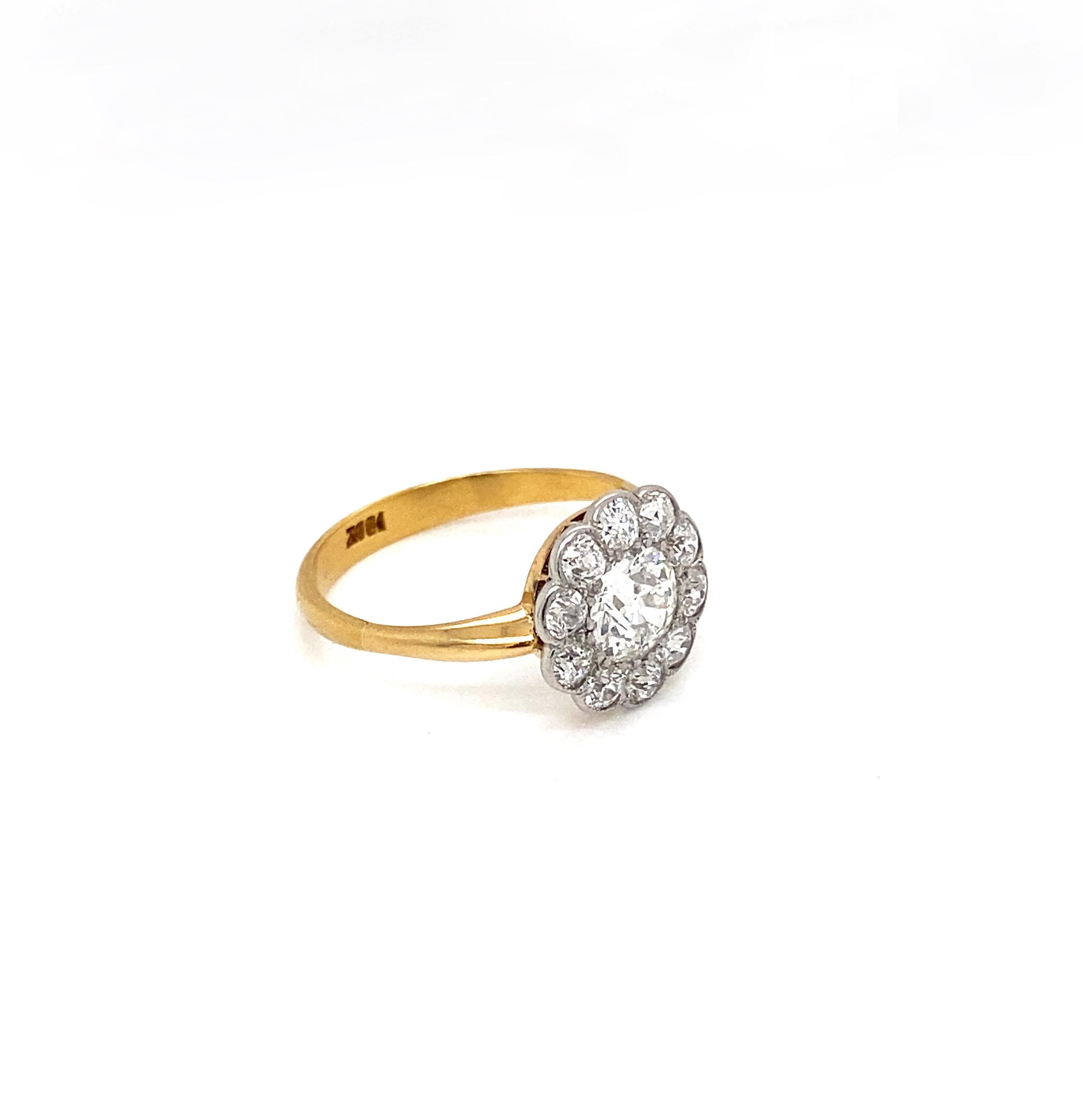 Introducing an authentic antique flower cluster engagement ring, finely crafted in luxurious 18 carat yellow and white gold.

At its heart, the wonderful ring features a striking old European cut diamond, securely held in place by a multi claw, open