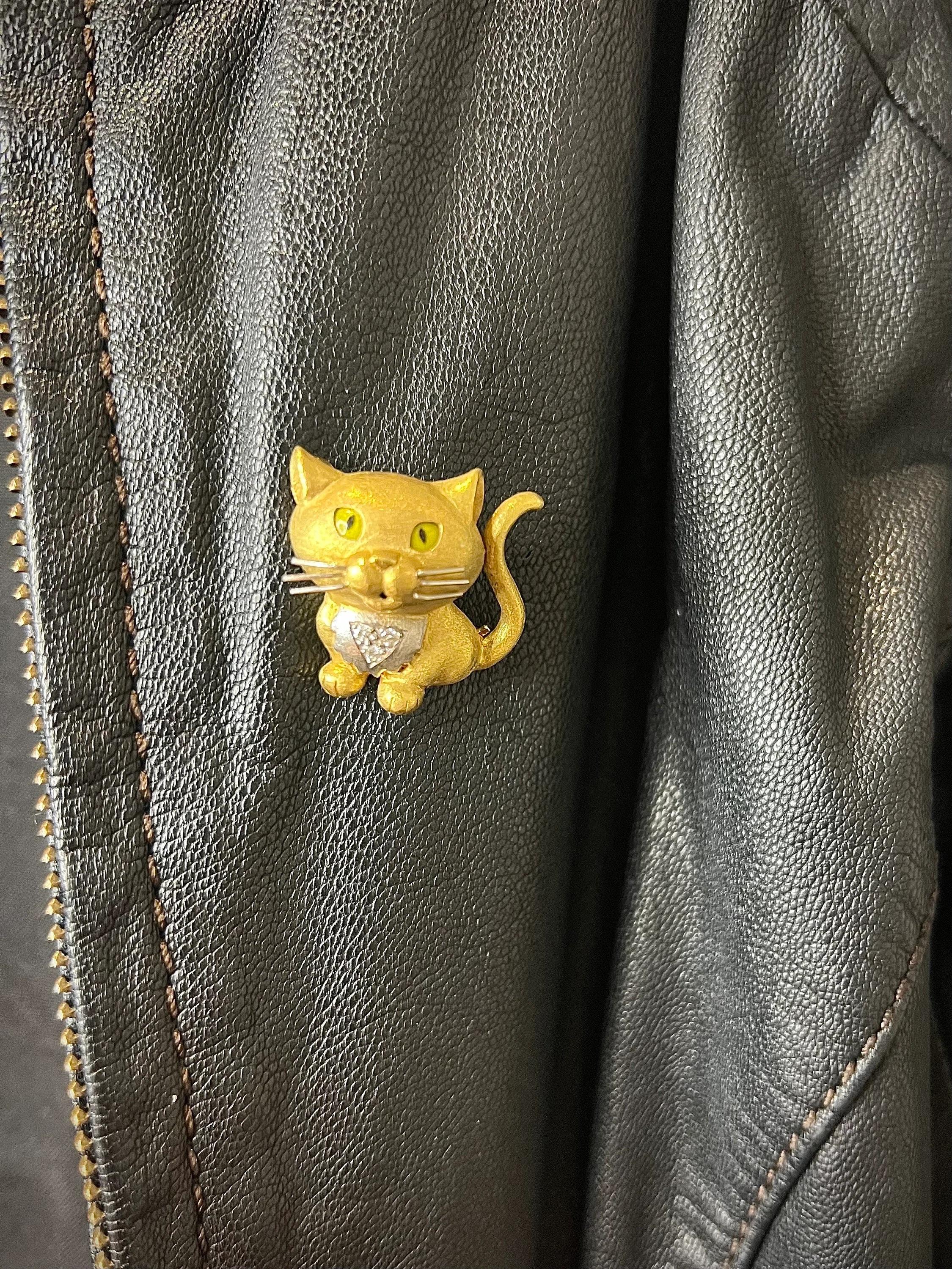 Vintage Cat Brooch

18ct Gold Stamped 750

Circa 1980s

Makers Mark E W & Co

Indulge in a piece of vintage elegance with this 18ct yellow matt gold cat brooch. The brooch boasts yellow enamel eyes and white gold whiskers that add a touch of