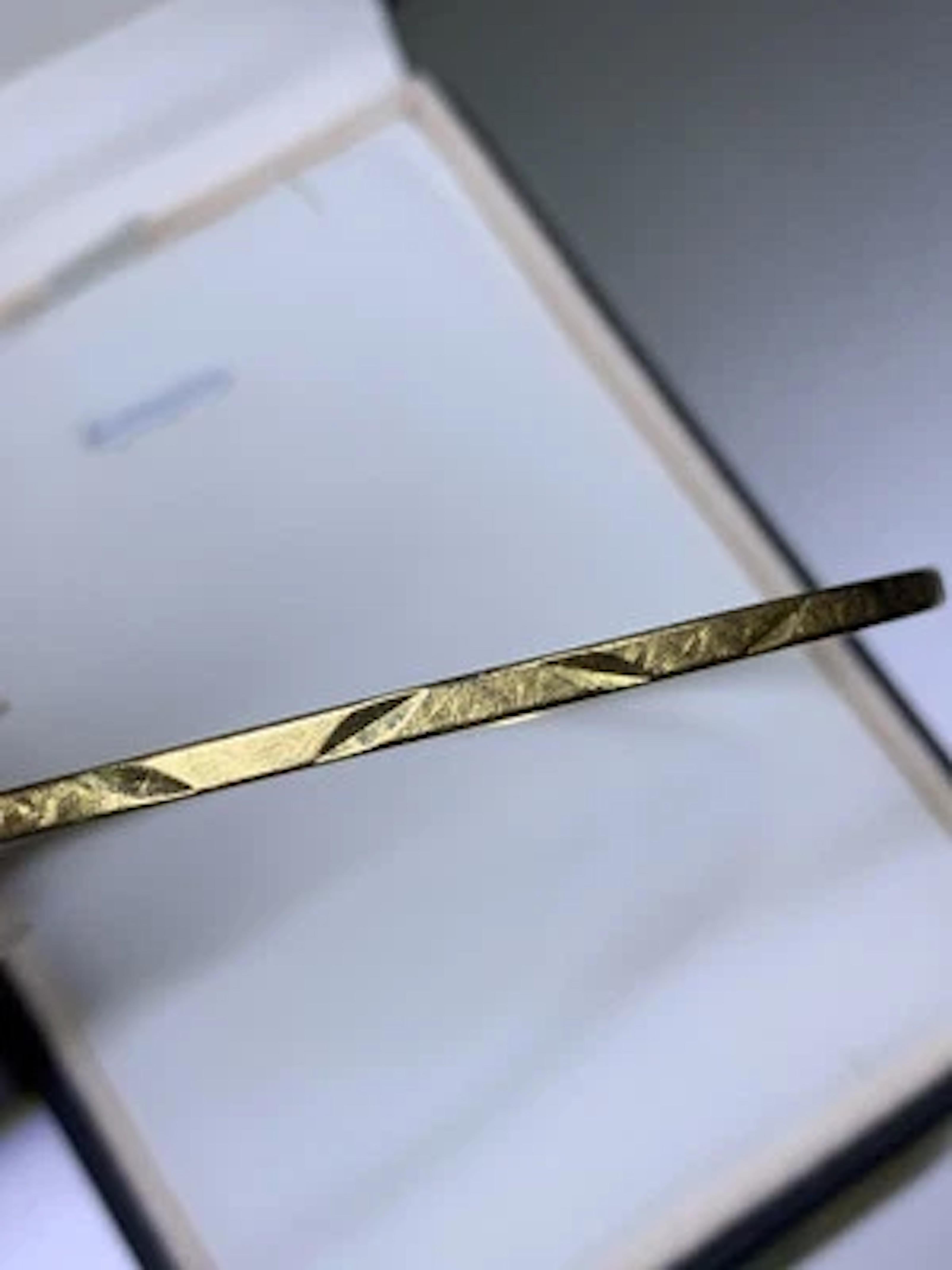 Fabriqué en or jaune 18ct luxueux, ce bracelet bangle épais exsude une élégance intemporelle. La pièce, qui pèse 4,2 grammes et mesure 7 3/4 pouces, est une déclaration de sophistication avec sa couleur dorée élégante et son design classique. La