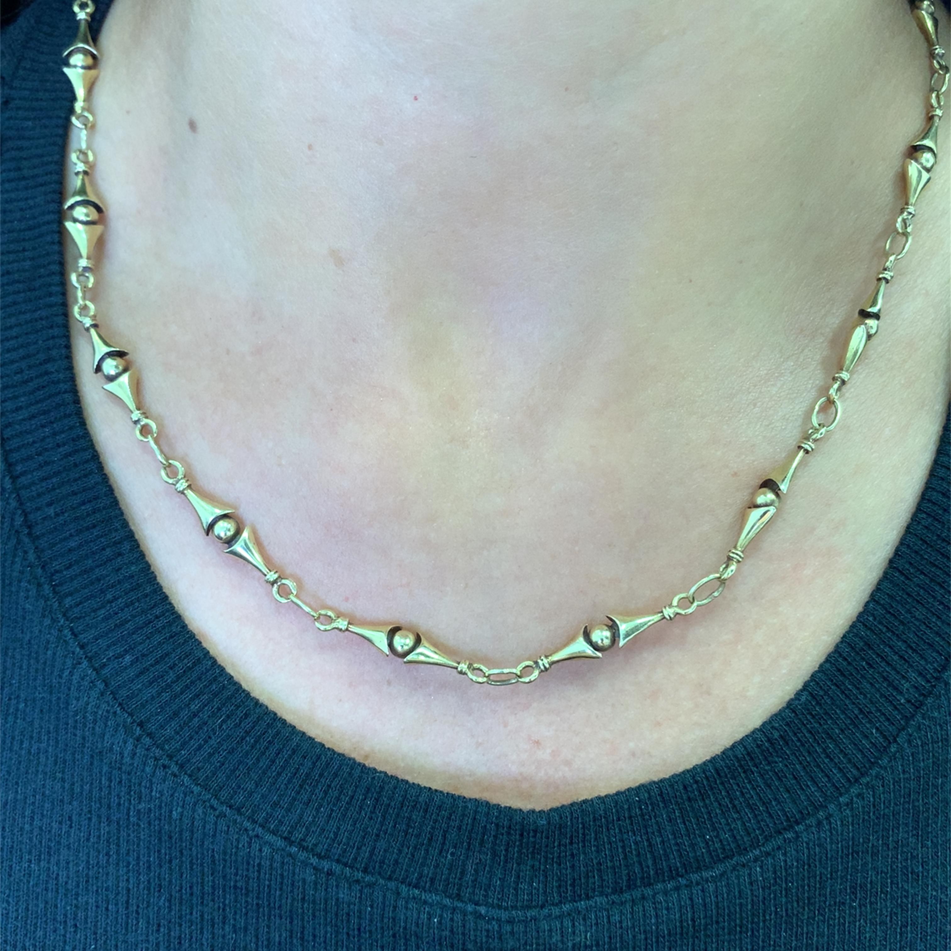 Eleva tu estilo con este exquisito collar de cadena de oro amarillo de 18 quilates. La cadena presenta una serie de elementos alargados de intrincado diseño, cada uno separado por eslabones de conexión, que crean un armonioso equilibrio de forma y