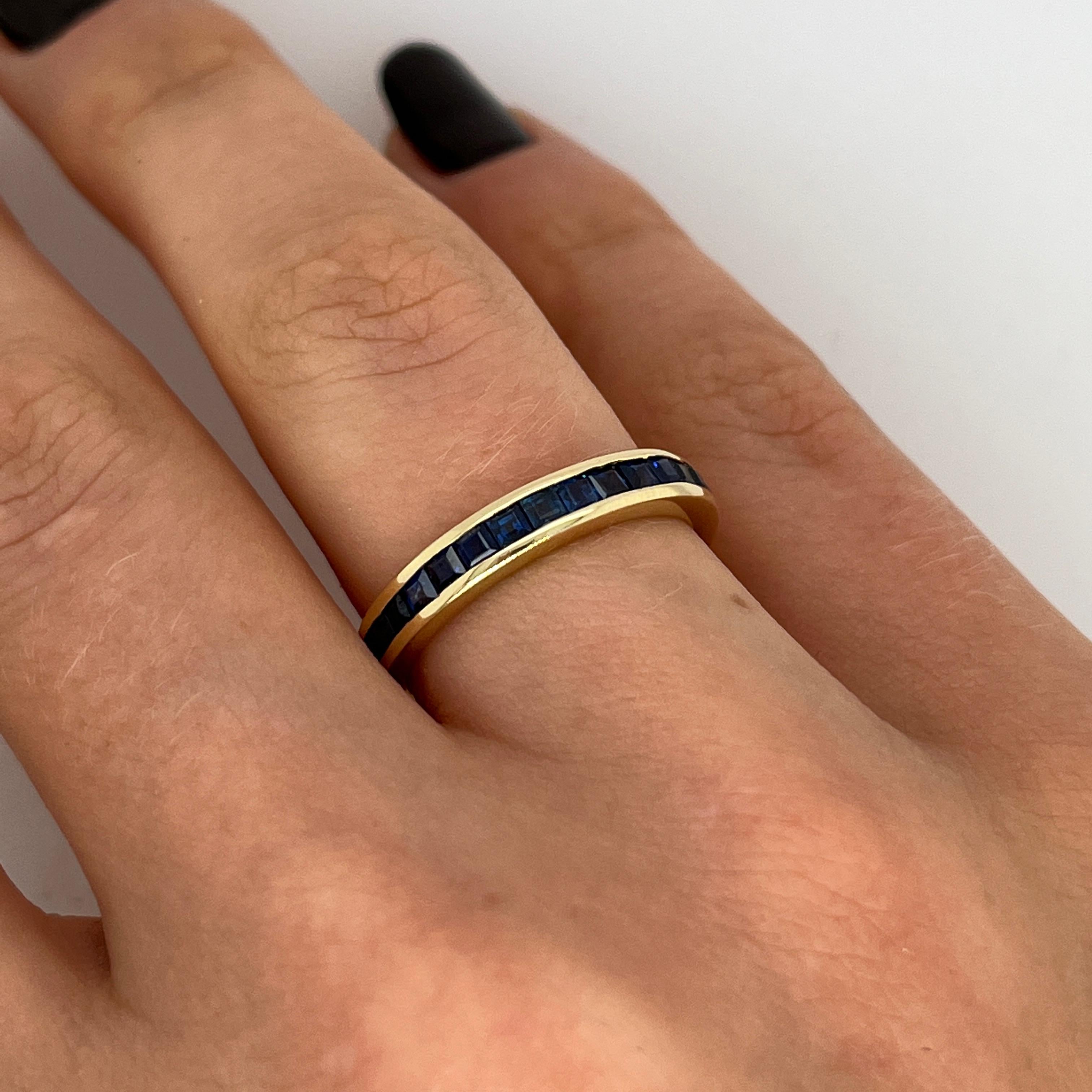 Élégante et intemporelle, cette demi-bague d'éternité est fabriquée en or jaune massif 18ct et sertie sur tout le pourtour de saphirs de taille princesse éclatants. Une bande continue d'un bleu profond et brillant, parfaite pour être empilée ou