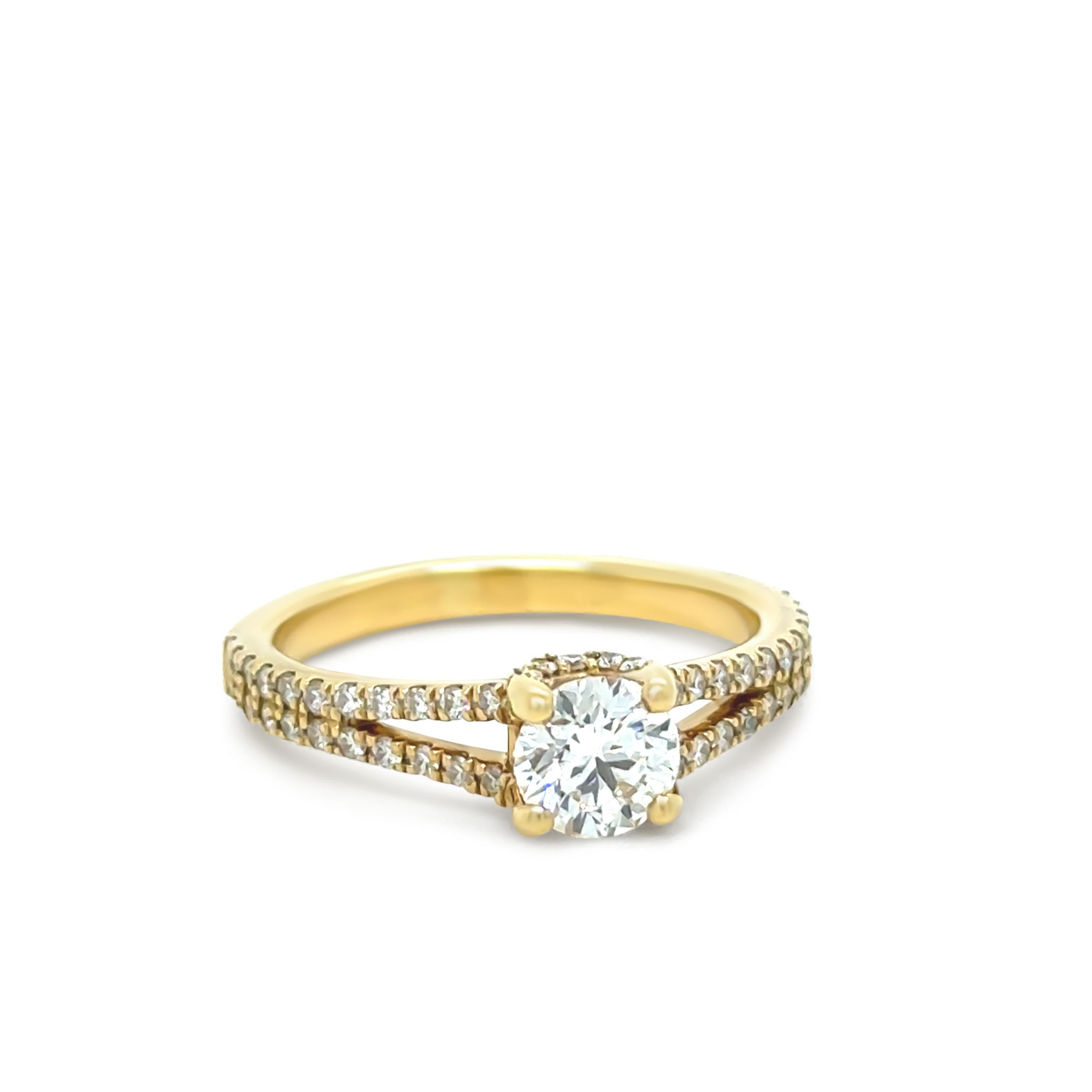 Cette magnifique bague en or jaune 18ct est ornée d'un diamant rond de 0,60ct de taille brillant, serti dans un design classique à quatre griffes. Le diamant principal, portant l'inscription au laser 