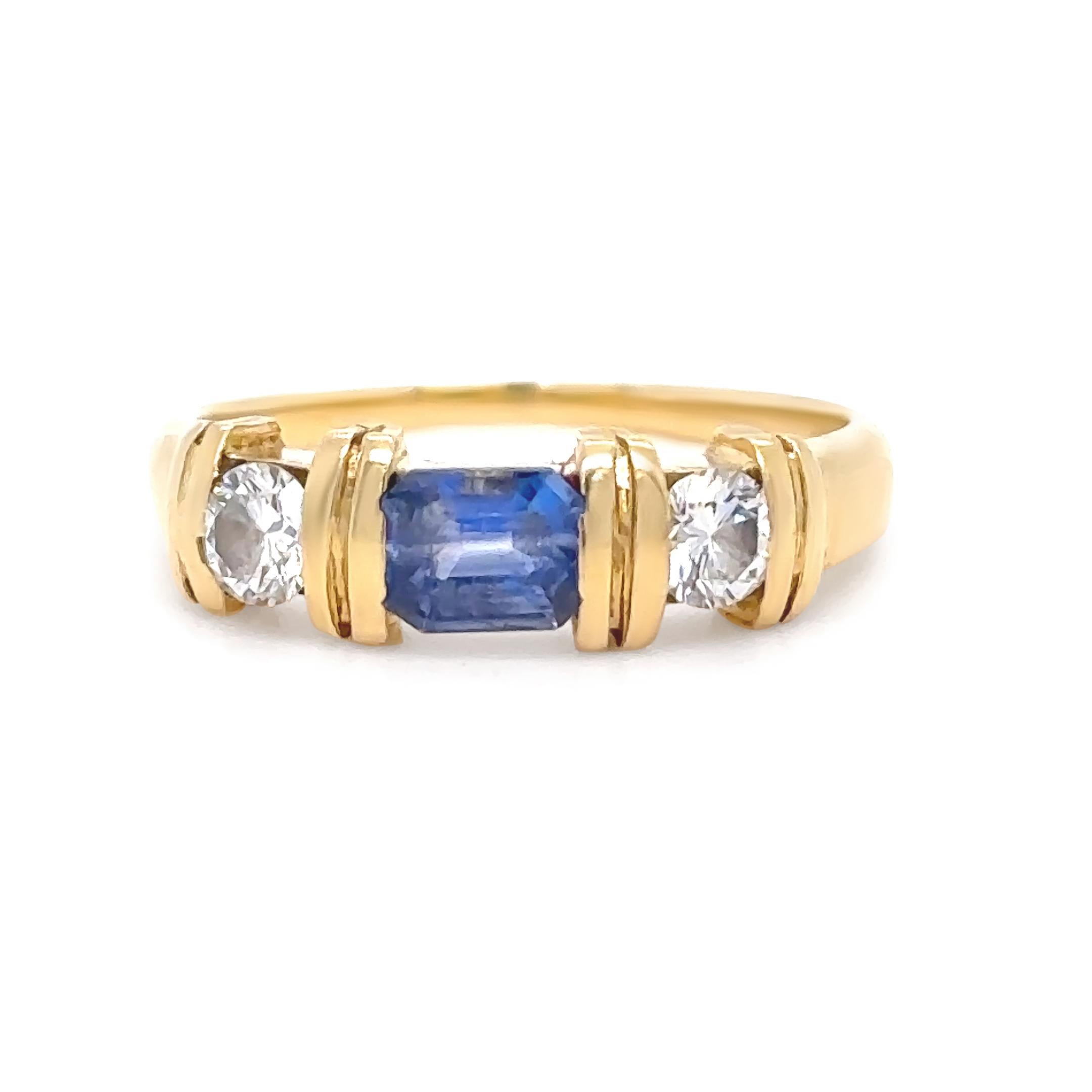 This elegant ring is crafted in 18ct yellow gold and showcases a striking emerald-cut sapphire, end-set with precision. The sapphire measures approximately 4.40 x 3.30 x 2.59mm, weighing an estimated 0.40ct, and displays a rich medium blue colour