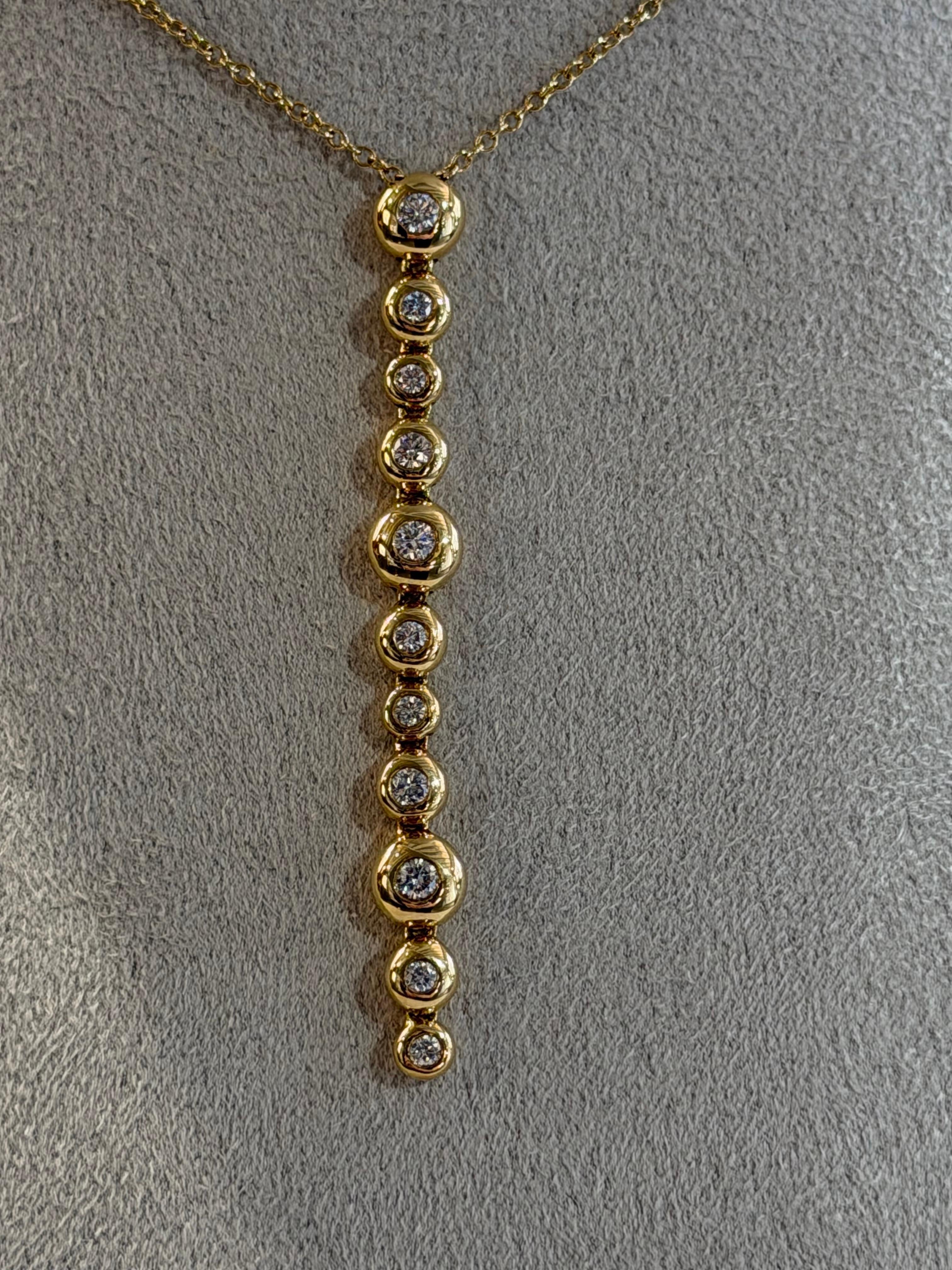 Elegancia sin esfuerzo con un toque moderno: este delicado colgante encarna la sencillez refinada y la belleza luminosa. Elaborada por expertos en oro amarillo de 18 quilates, presenta una elegante línea vertical de motivos de burbujas suavemente