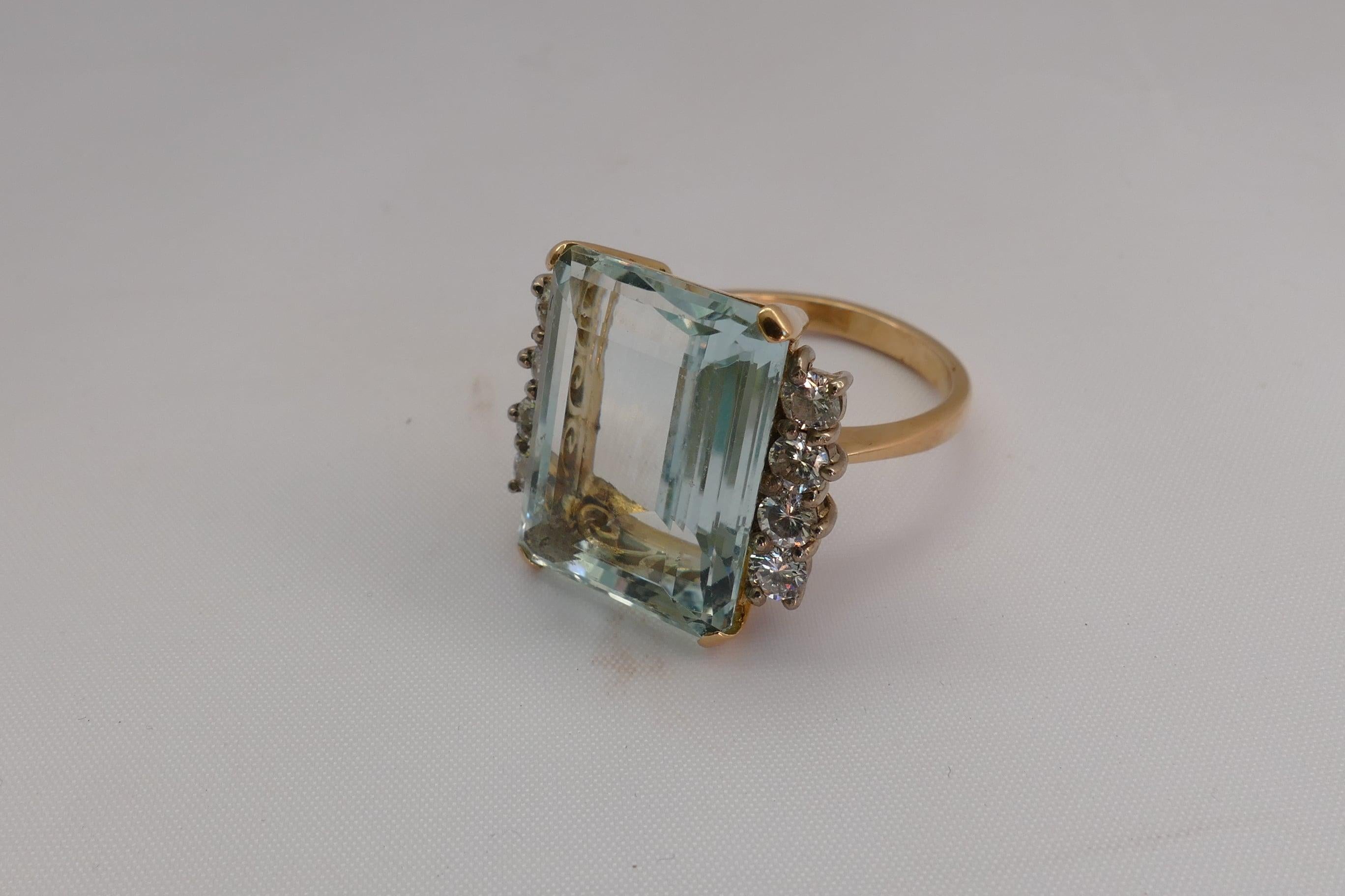 This Art Deco Style, but possibly genuine Art Deco Emerald Cut Aquamarine Stone is a large beautifully translucent sea blue/green, claw set, flanked by 8 Round Brilliant Cut Diamonds, Colour H/I and Clarity SI1-SI2.
The Band is polished, low half
