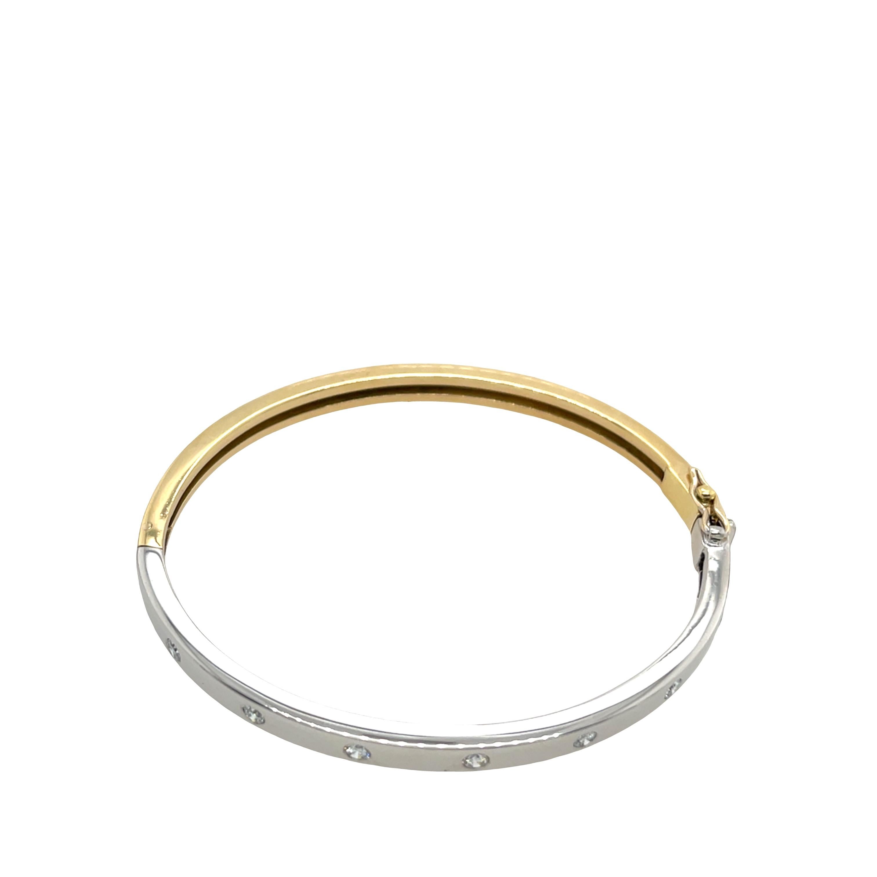 Precioso brazalete bicolor de oro amarillo y blanco de 18 ct, elegantemente diseñado y engastado con 7 brillantes diamantes naturales de talla brillante redonda, que suman un total de 0,30 quilates. El pulido contraste del oro amarillo y blanco