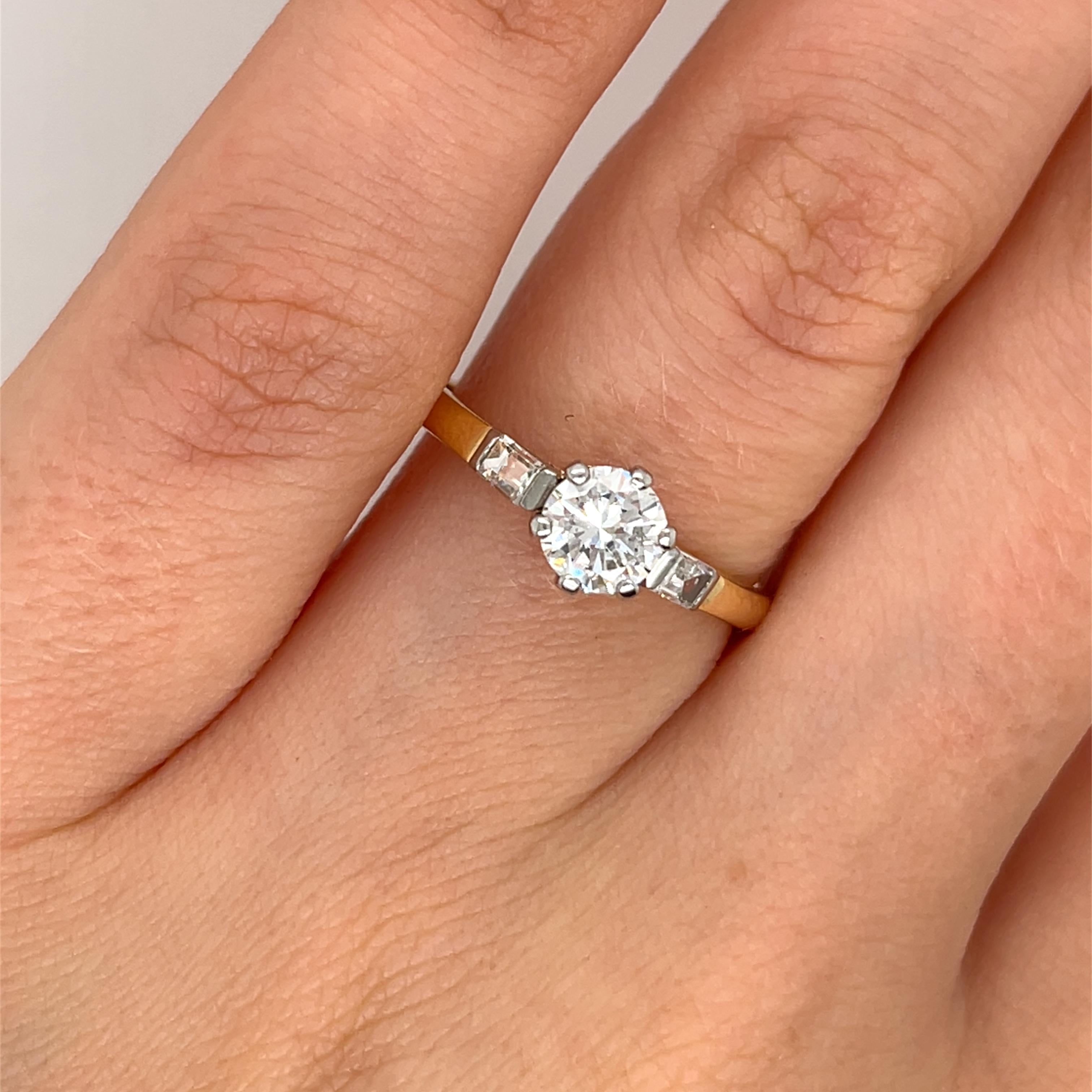 Ein klassischer Diamantring mit einem runden Brillanten von 0,50 Karat, wunderschön gefasst in einer Mischung aus 18 Karat Gelb- und Weißgold, besetzt mit 2 passenden Baguettes.
Das Design kombiniert die Wärme von Gold mit Weiß.
Gesamtgewicht der