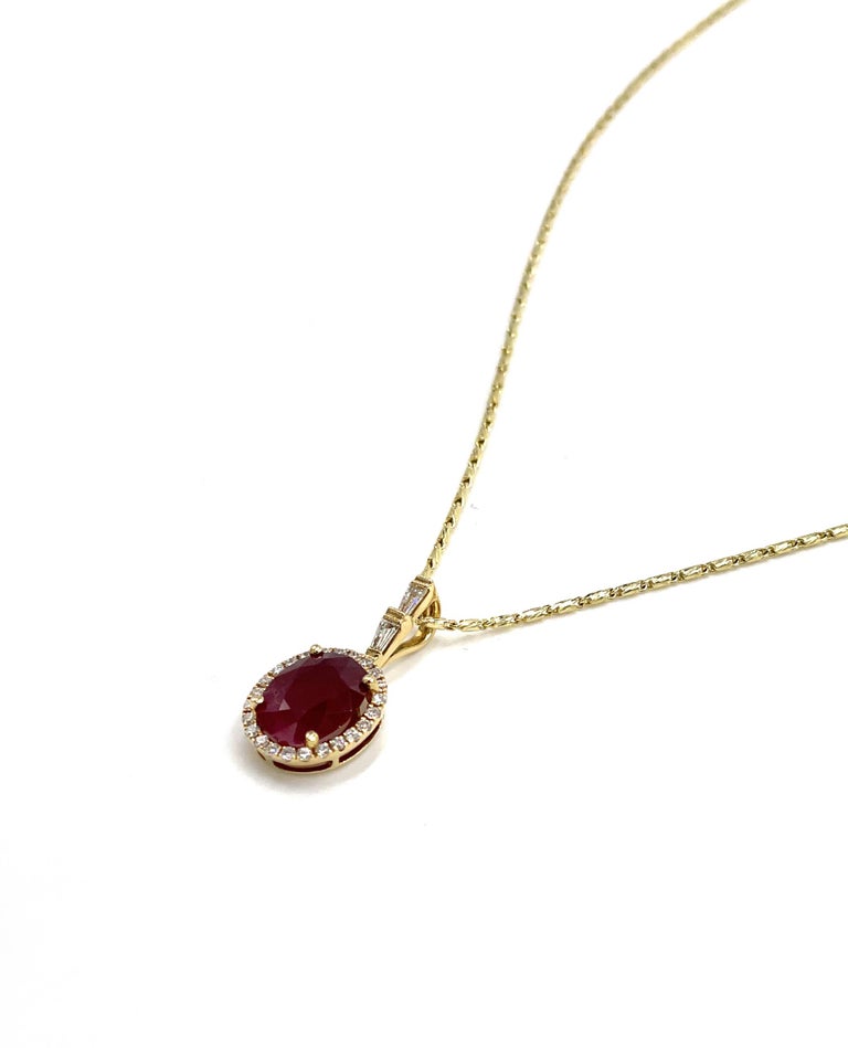 18K yellow gold halo pendant with one oval ruby weighing 2.69 carats. The pendant is furnished with 24 round diamonds and two tapered baguette diamonds with a total weight of 0.29 carat. The pendant slides on a 14K yellow gold 18 inch chain.