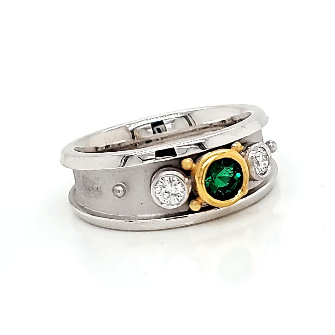 At the heart of this ring is a round emerald, 0.25 carats, nestled between two round diamonds, 0.2 carats each, all delicately set in bezels. 

Crafted in a blend of 18k and 22k gold, weighing 8.1 grams.

This ring boasts a perfect balance of