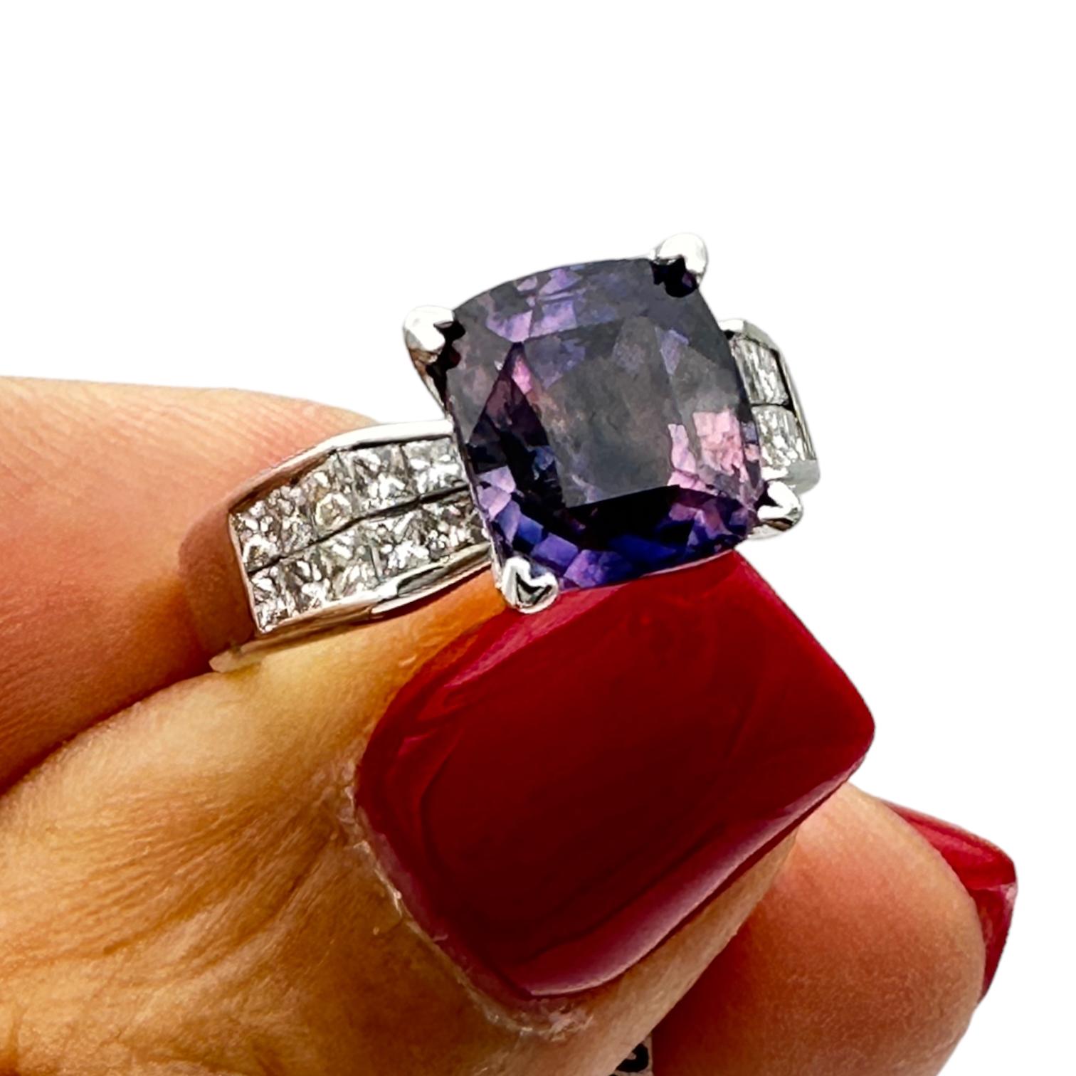 18 karat white gold ring showcases a rare, cushion cut purple sapphire solitaire diamond ring. The sapphire measures 9.18-8.05 x 5.58 mm and weighs 3.98 carats. The color of the sapphire is purple with a blue tone and is cushion cut, set into four