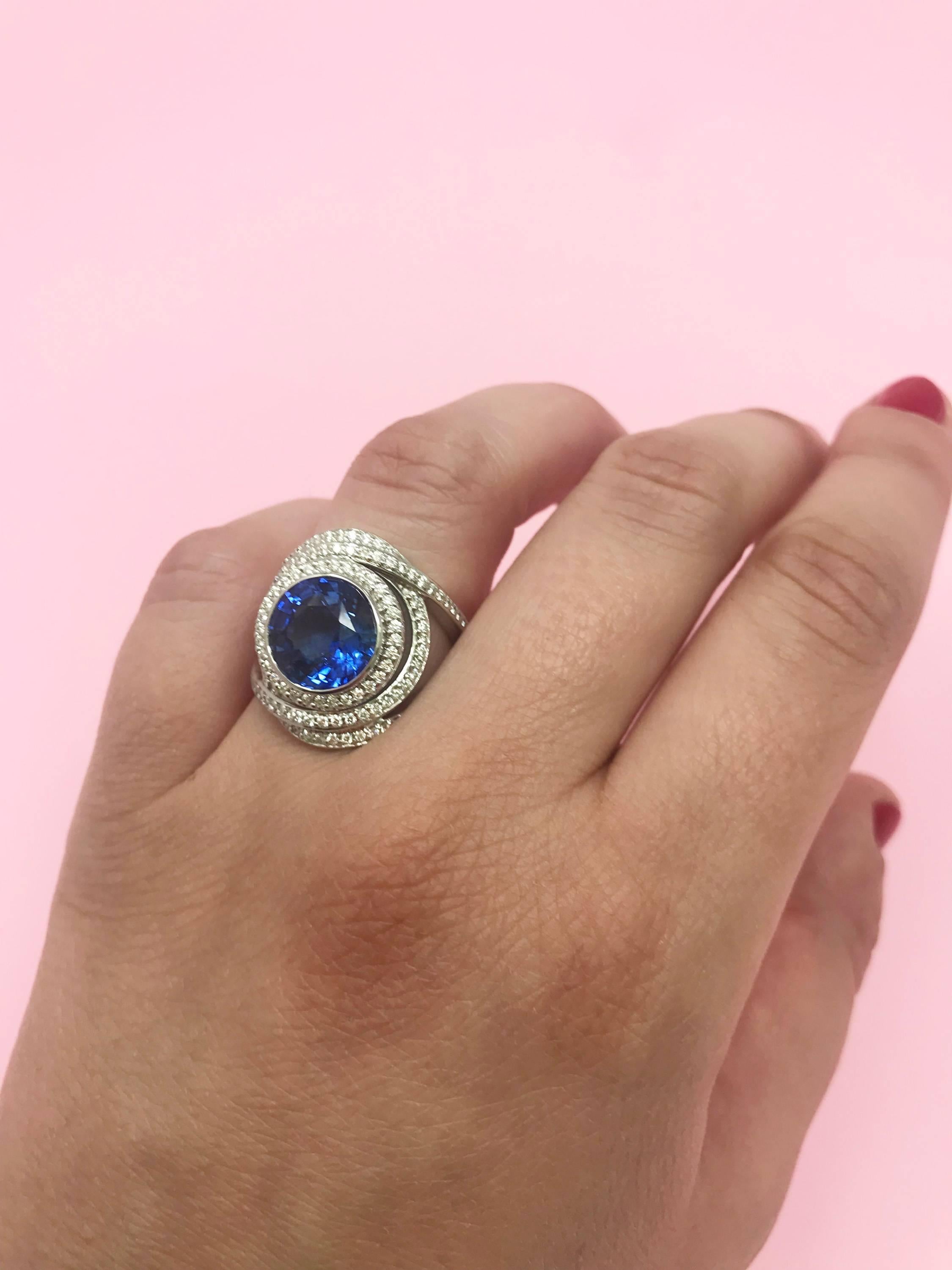 A stunning 5.31 carat Ceylon blue sapphire is the centerpiece of this 18 karat white gold ring, which is accented by swirls of .82 carats of dazzling GH-VS diamond pave.  The ring measures 2 cm tall and 1.7 cm across and has a 3.5 mm split shank for